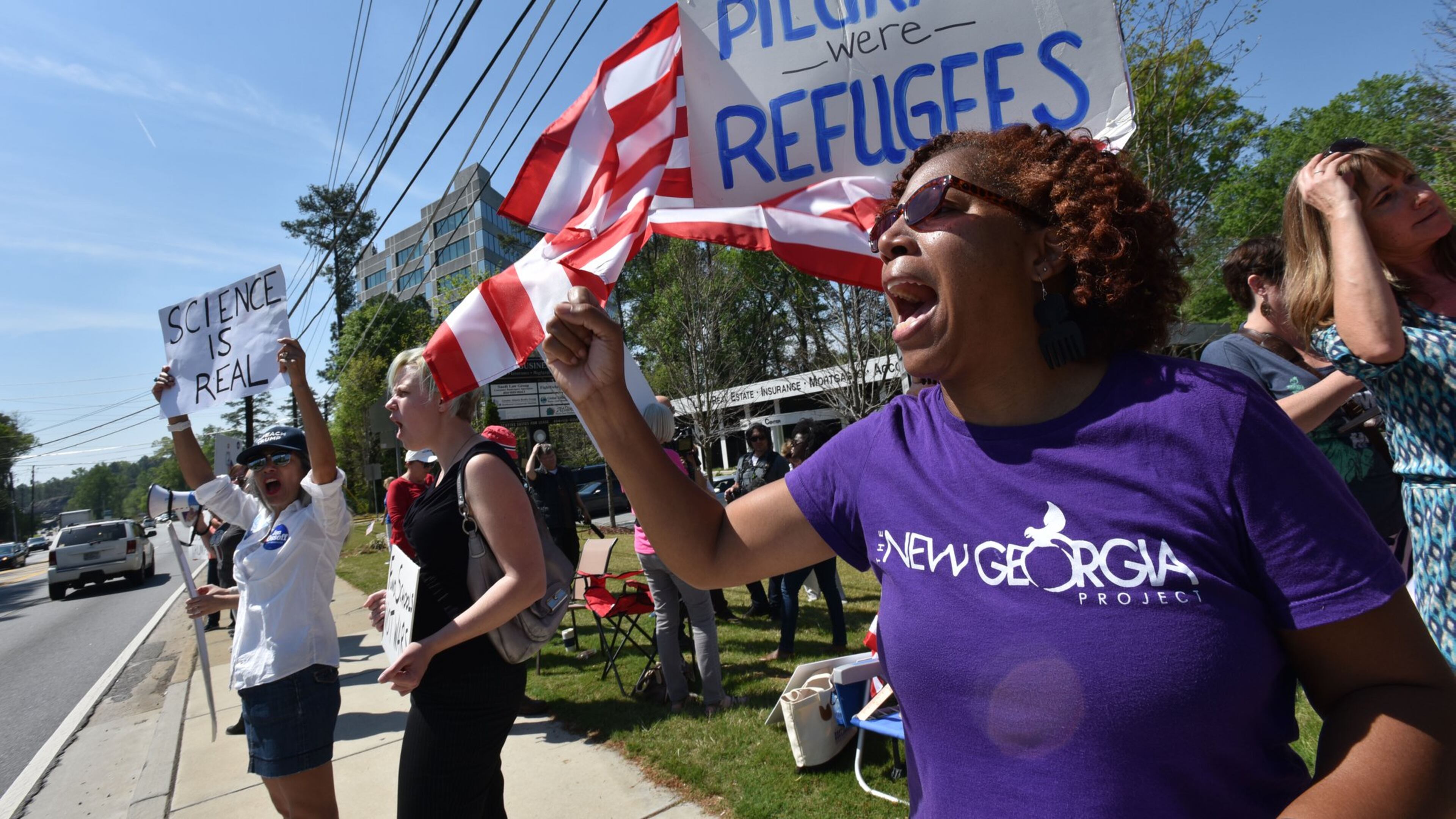 A group of demonstrators demands that U.S. Sen. David Perdue, R-Ga., hold a traditional town hall meeting during their protest Tuesday on Clairmont Road near a hotel where Perdue was set to speak during a business luncheon. HYOSUB SHIN / HSHIN@AJC.COM