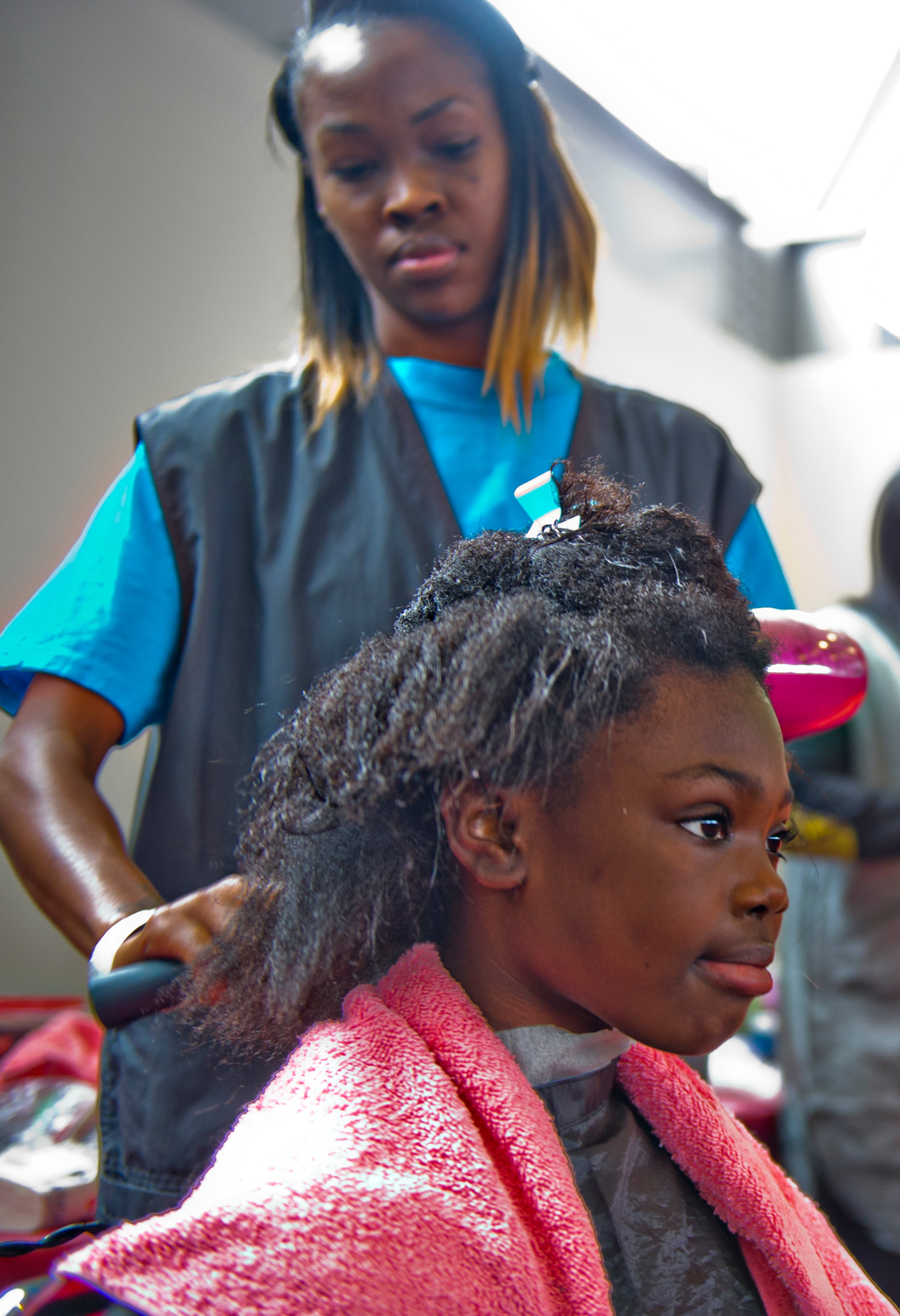 Trinity Bryant (bottom) gets her hair trimmed by Takilla White during the 44th annual Hosea Feed the Hungry and Homeless Thanksgiving Holiday Dinner at the Georgia World Congress Center in Atlanta on Thursday, November 27, 2014. The annual event feeds thousands of homeless people around the metro area as well as provides showers, haircuts, clothes and other critical serves at no cost.