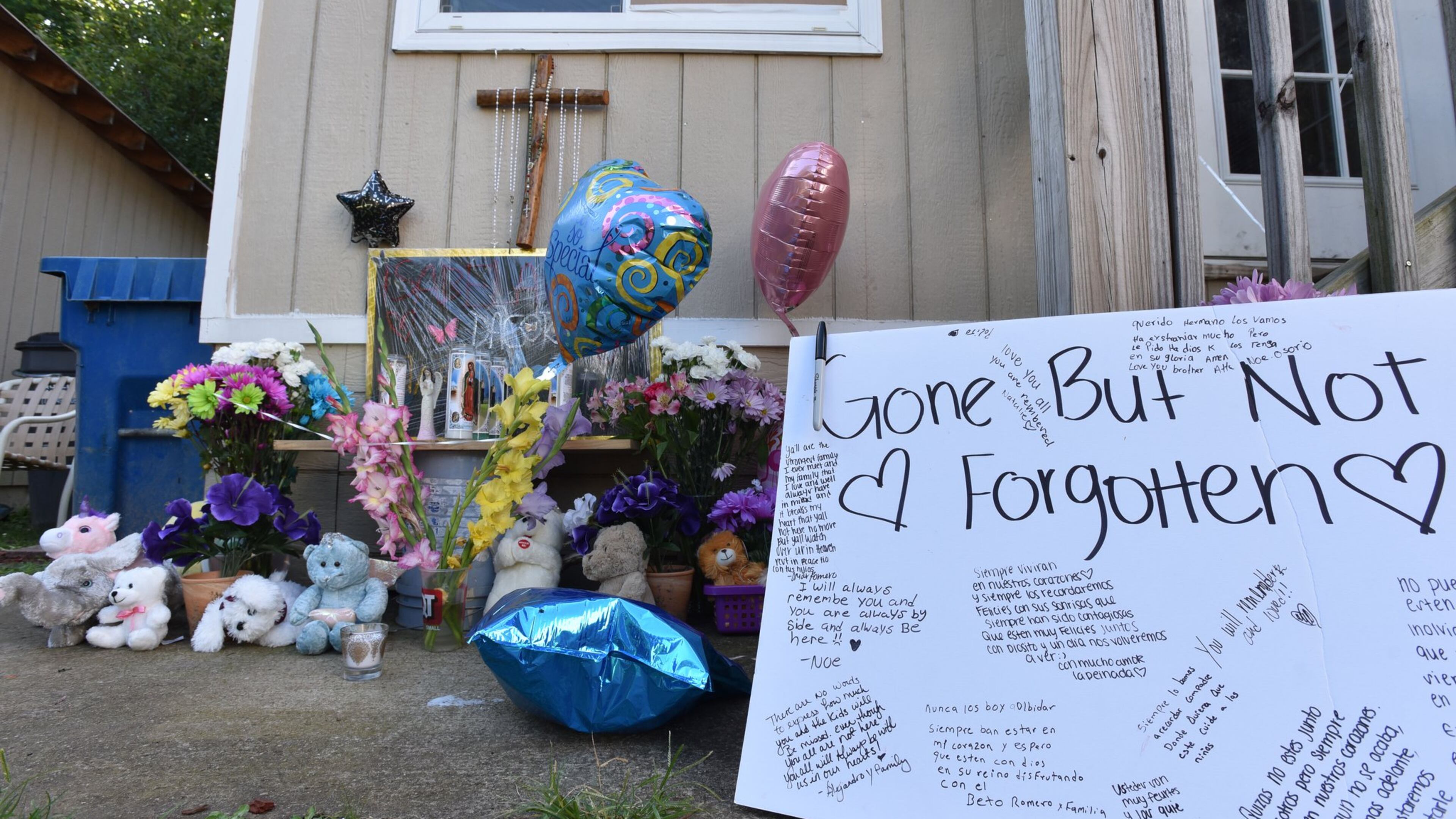 Neighbors and friends placed flowers and messages Thursday night during their gathering on the doorstep of the home where the murders occurred. HYOSUB SHIN / HSHIN@AJC.COM