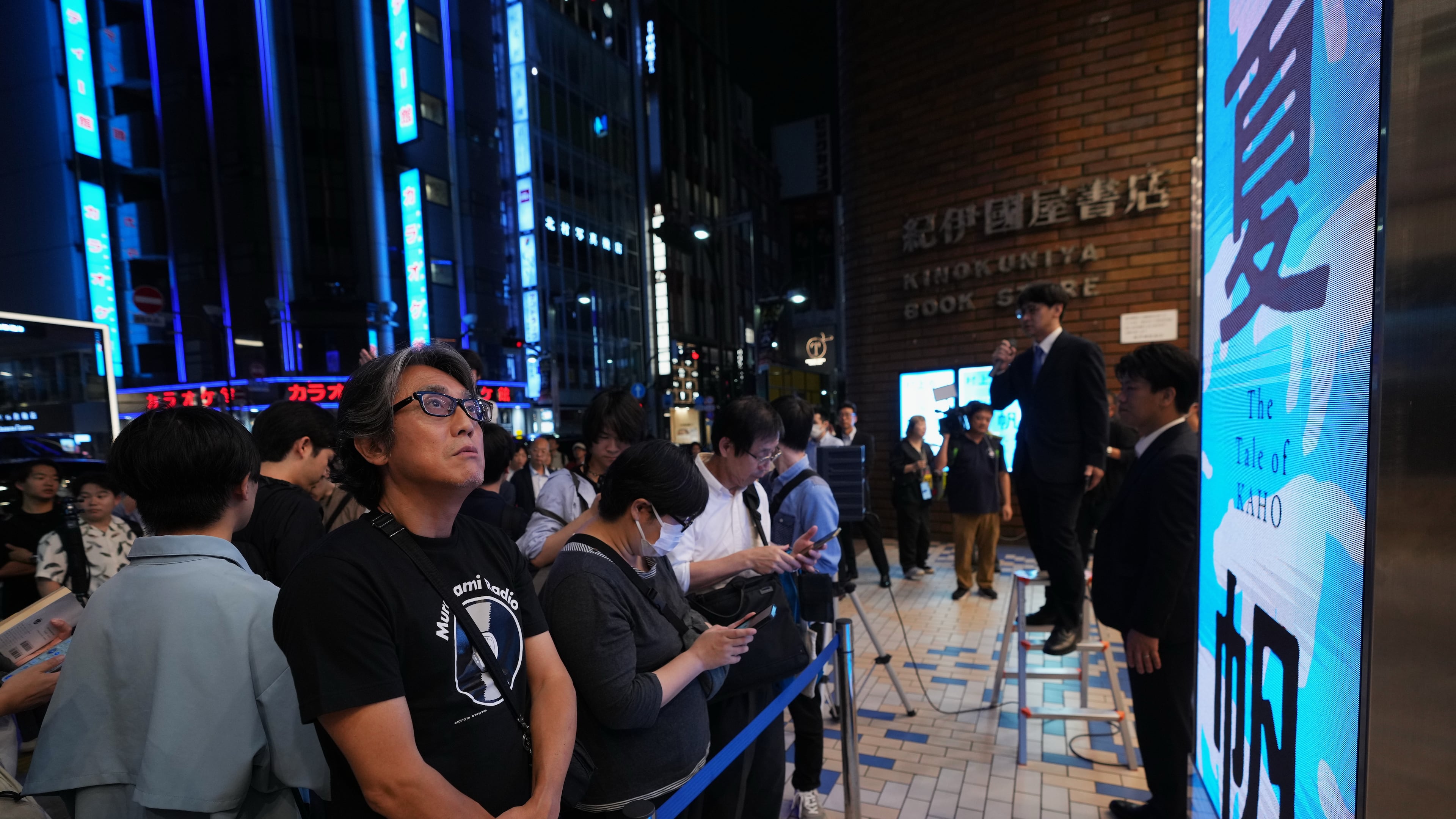 People attend a countdown event to receive copies they pre-purchased, of Haruki Murakami's new book, titled "The Tale of KAHO" after the clock strikes midnight, at a Kinokuniya bookstore in Tokyo on Thursday, July 2, 2026. (AP Photo/Hiro Komae)