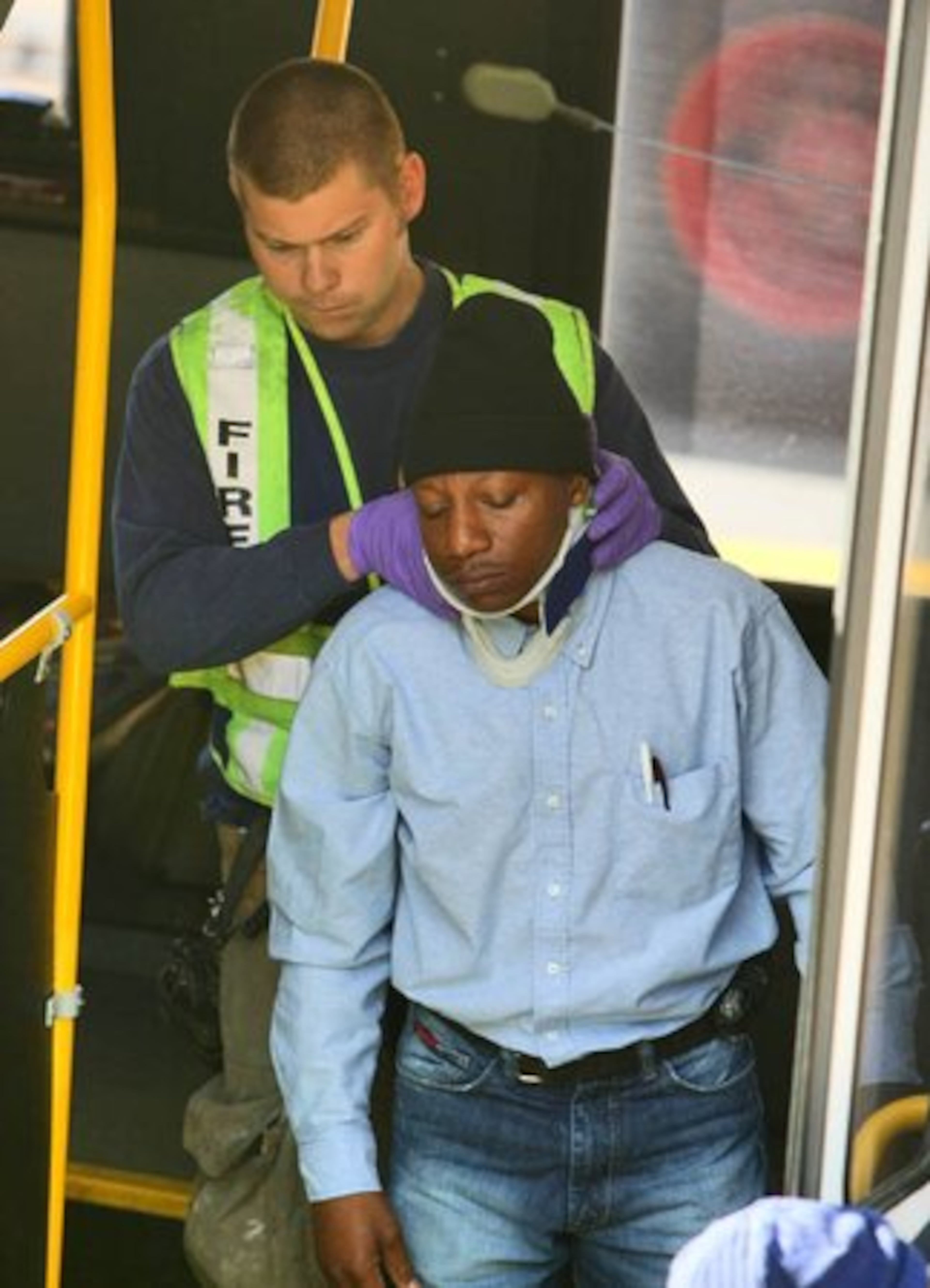 A bus passenger is helped off by an emergency worker.