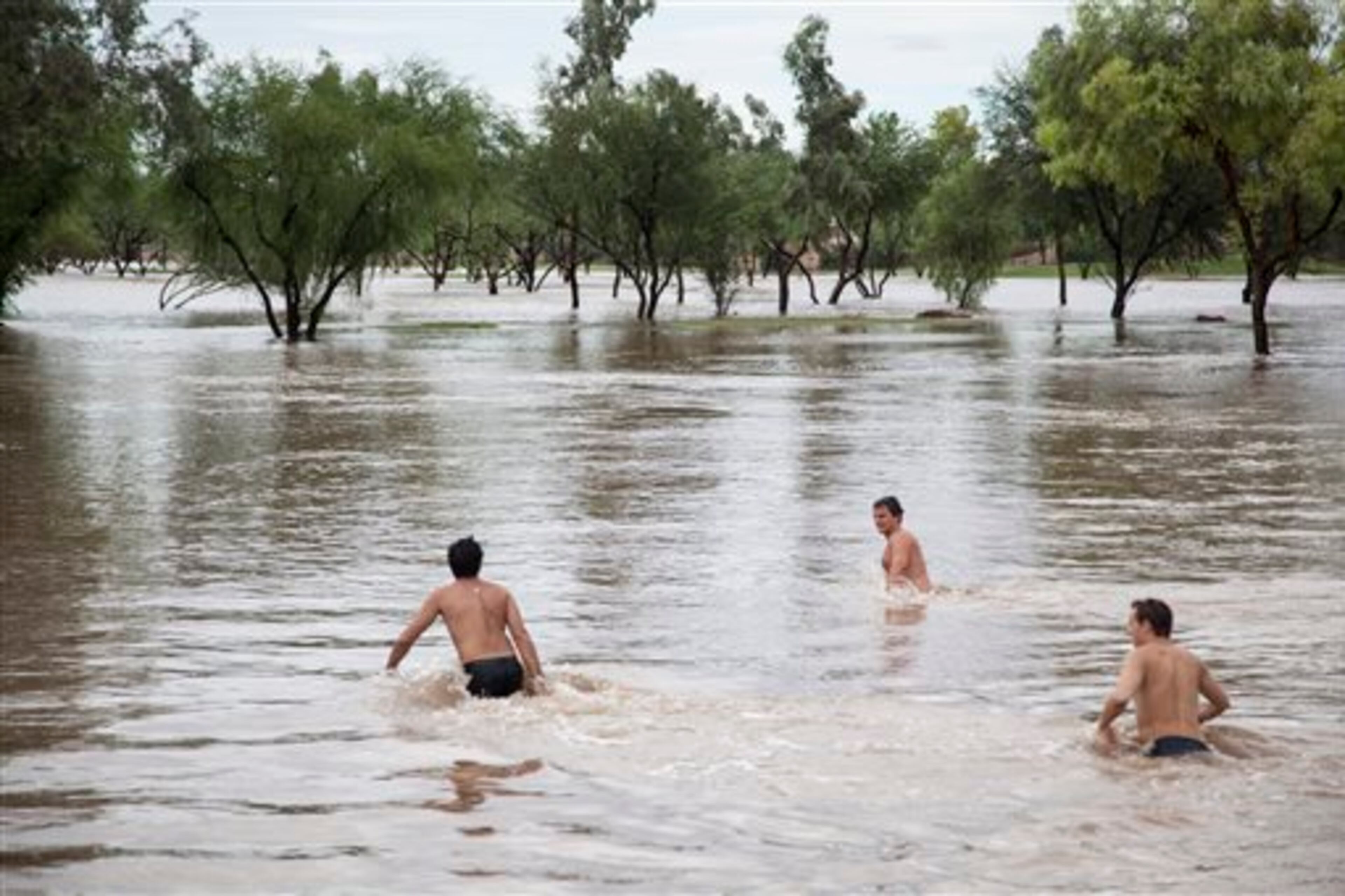 Saguaro High School Seniors, from left, Brad Khnanisho, Michael Panka and Shaun Younger spend time time in the Indian Bend Wash during the flooding in Scottsdale, Monday, Sept. 8, 2014. (AP Photo/The Arizona Republic, Dave Seibert) MARICOPA COUNTY OUT - NO MAGS- NO SALES - MANDATORY CREDIT