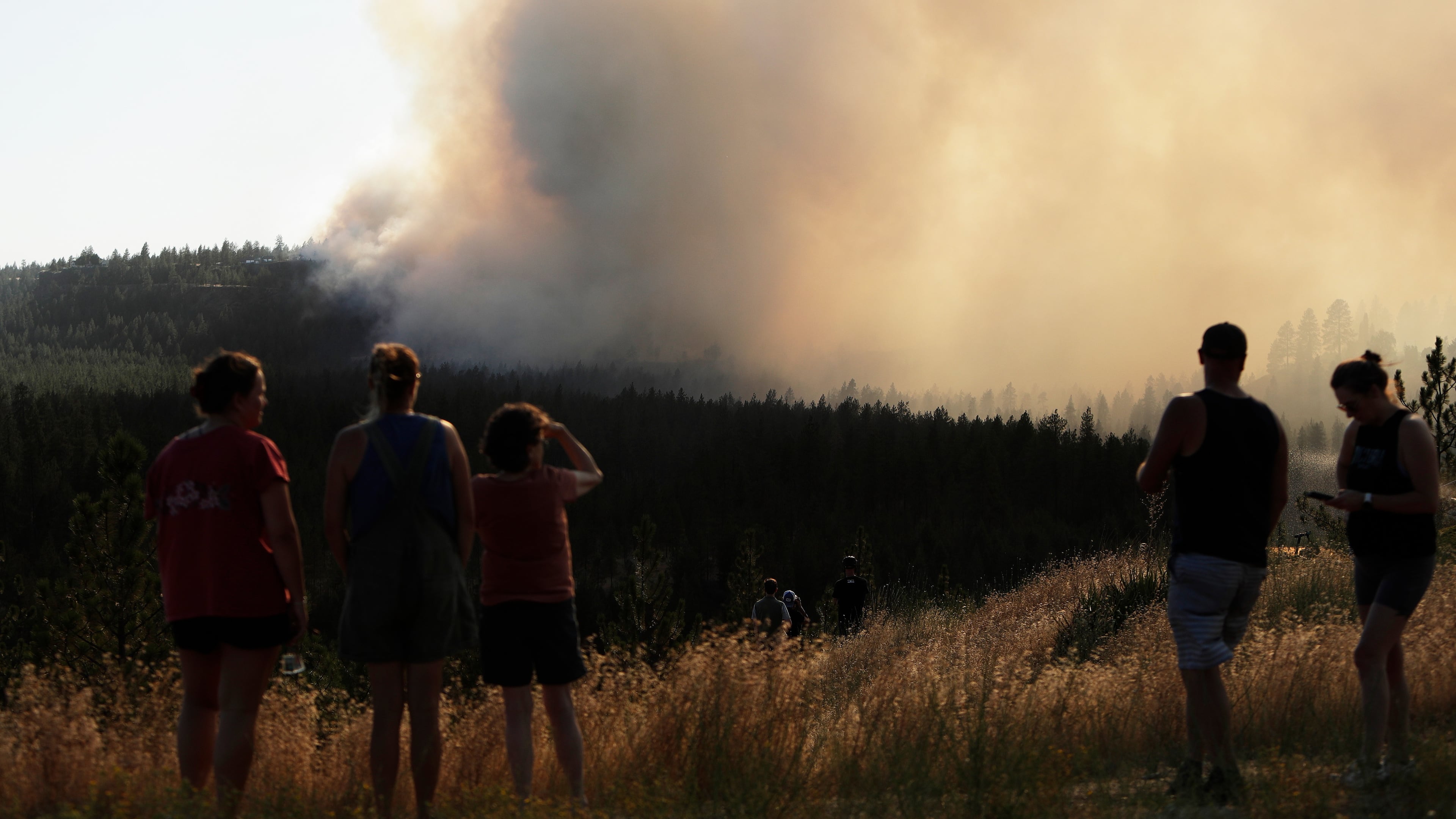 People watch Old Trails Fire from W. Northwest Blvd., Saturday, Aug. 1, 2026, in Spokane, Wash. (AP Photo/Young Kwak)