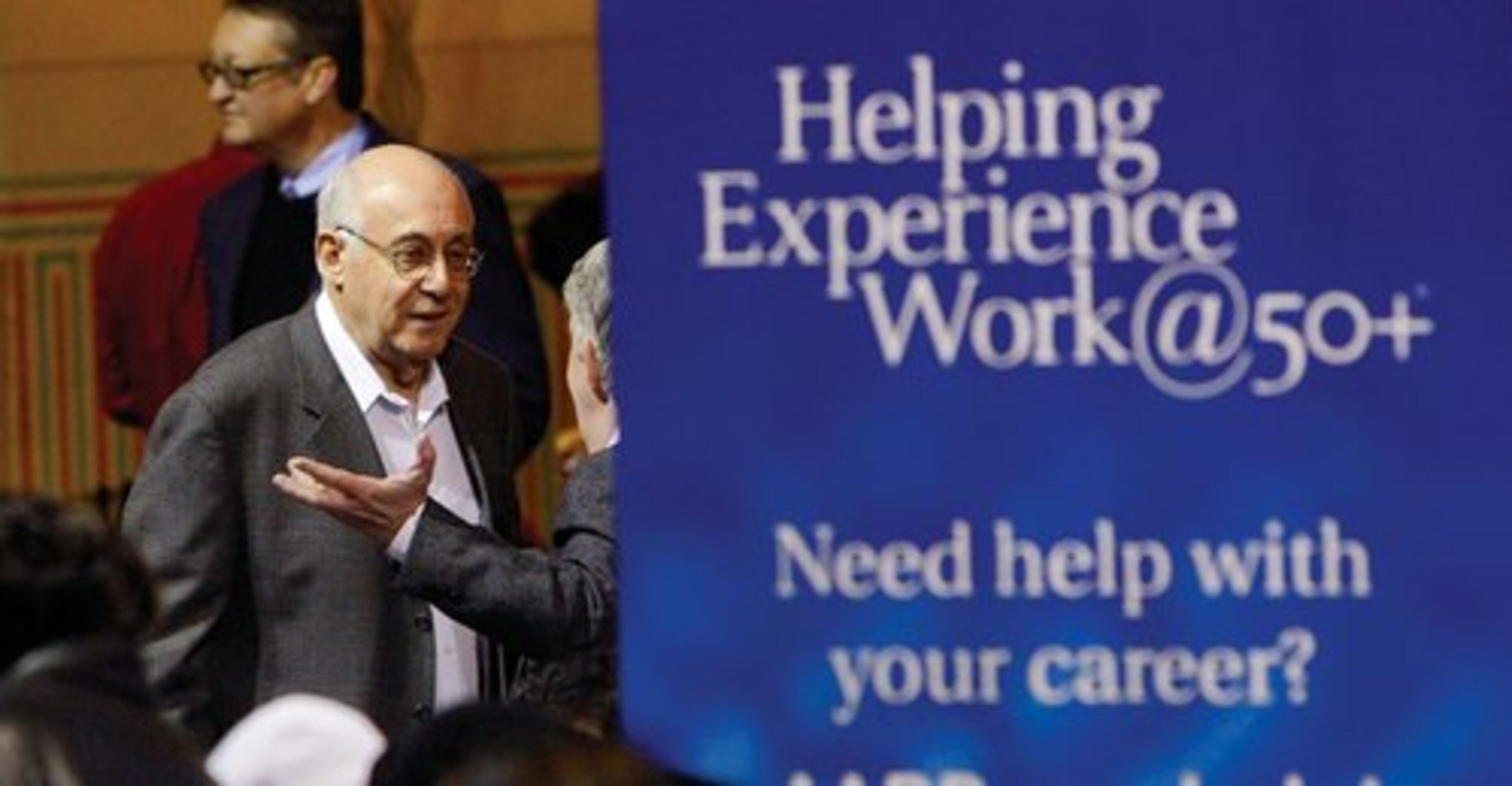 Job seekers Paul Breslow of Marietta (left) talks with Charley Smith (right) of Smyrna near a 50 + sign Monday. With unemployment climbing among older workers, AARP held a career fair March 22.