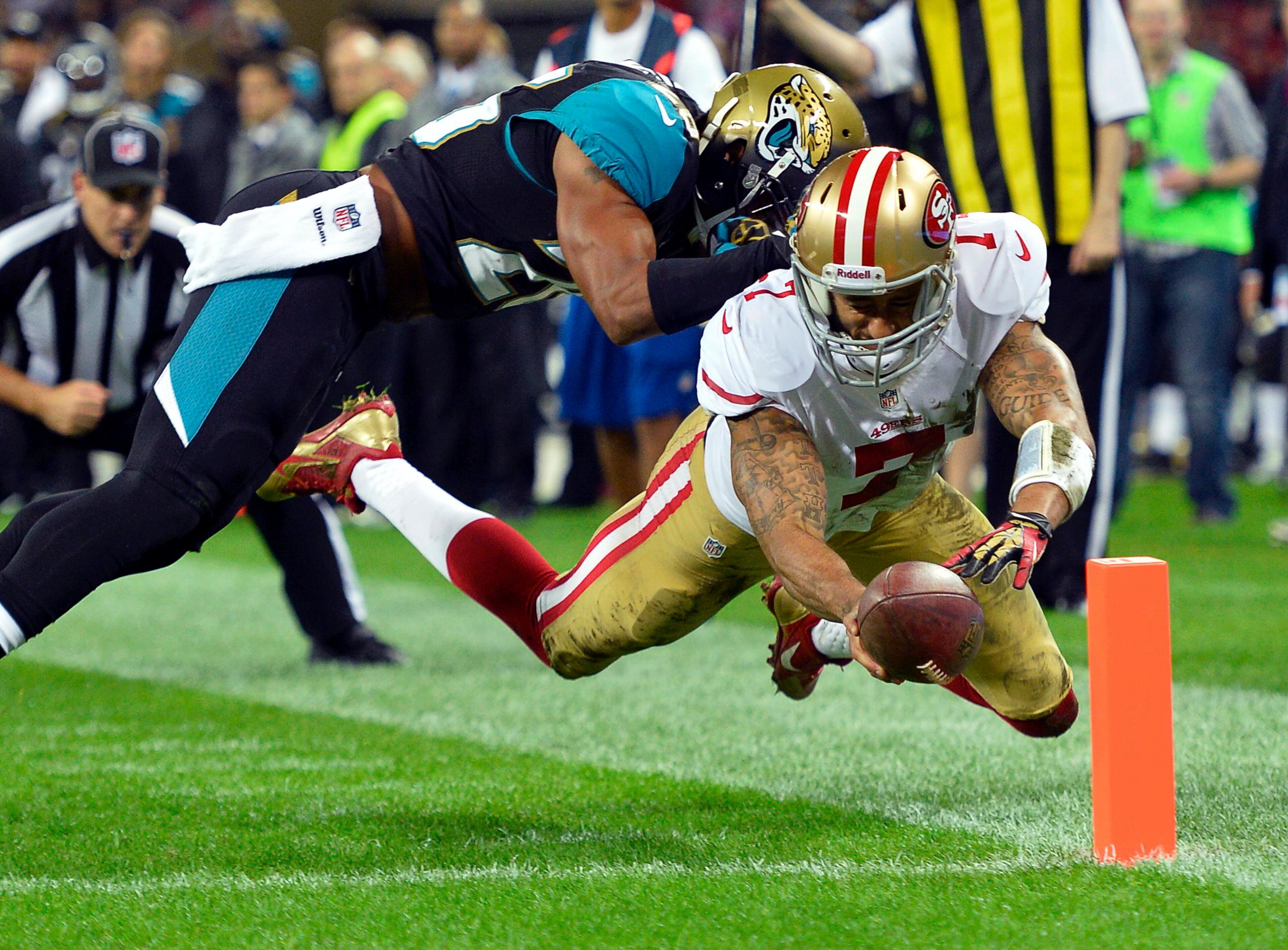 San Francisco 49ers quarterback Colin Kaepernick (R) scores a first quarter touchdown as Jacksonville Jaguars free safety Josh Evans (L) defends during their NFL football game at Wembley Stadium in London. The San Francisco 49ers beat the Jacksonville Jaguars 42-10. (REUTERS/Toby Melville)