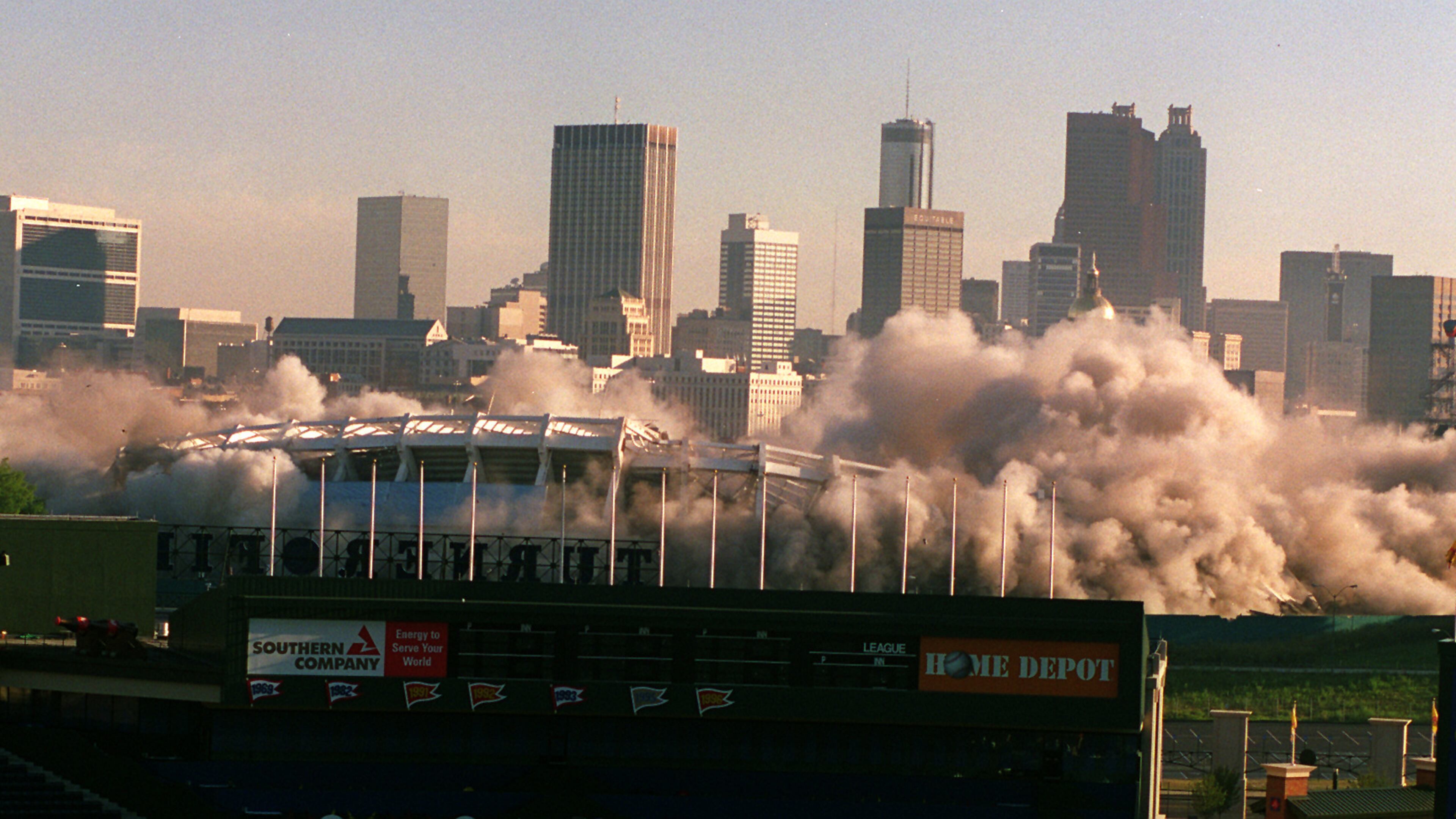 The imploding Historic Atlanta Fulton County Stadium is framed by the new Turner Field as it comes down with a series of 1,200 successive detonations. The space will be turned into 4,000 parking spaces. (AJC Staff Photo/Jonathan Newton)