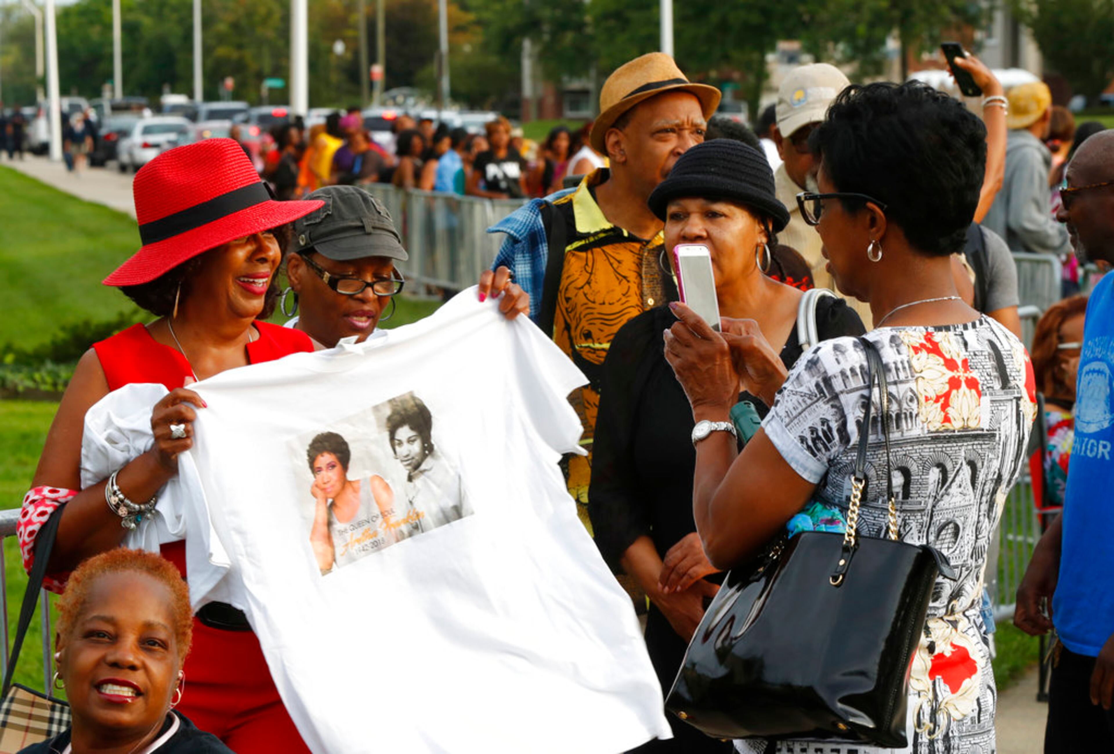People pose for photos while waiting in line outside the Charles H. Wright Museum of African American History during a public visitation for Aretha Franklin in Detroit, Wednesday, Aug. 29, 2018. Franklin died Aug. 16, 2018 of pancreatic cancer at the age of 76. (AP Photo/Paul Sancya)