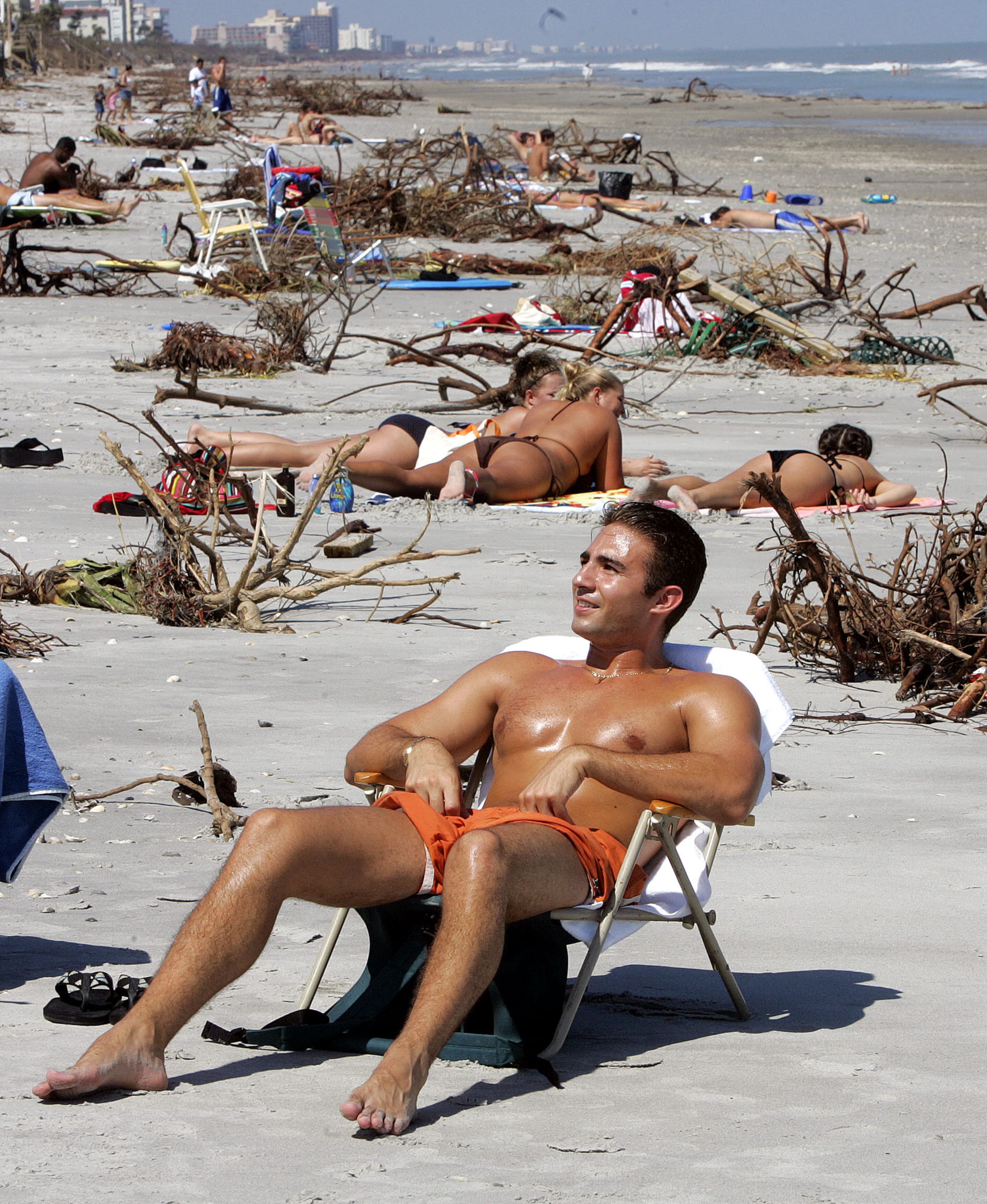 Rico Manna of Rome, NY., joins hundreds of others as they enjoy the sun on Indiatlantic Beach, Fla., on Tuesday, Sept. 28, 2004. Debris from Hurricane Jeanne litters the beach but hasn't detracted the beachgoers from returning to the coast. (AP Photo/Dave Martin)