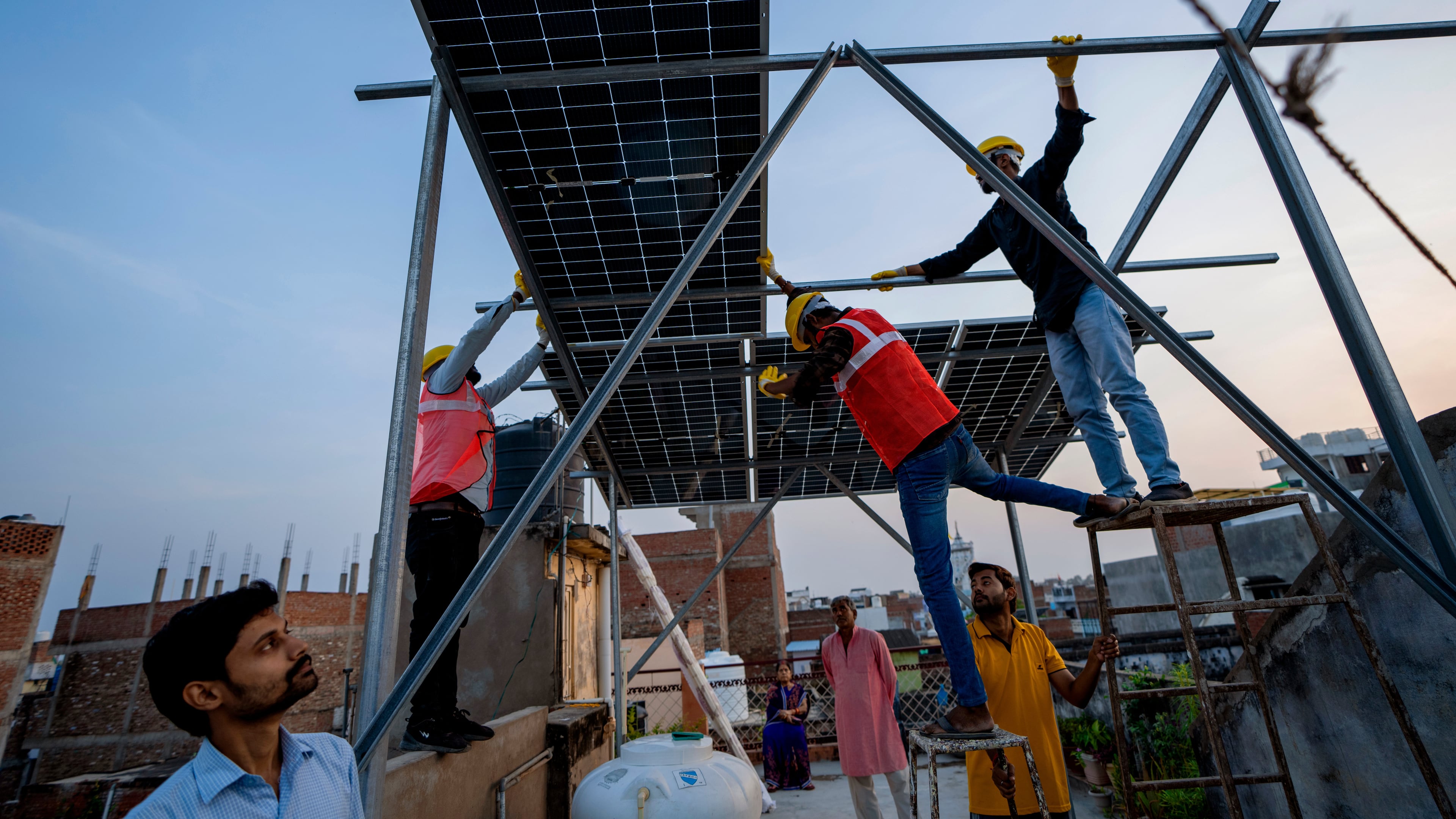 FILE - Workers install solar panels on a rooftop of a home in Prayagraj, India, Monday, Oct. 14, 2024. (AP Photo/Rajesh Kumar Singh, File)