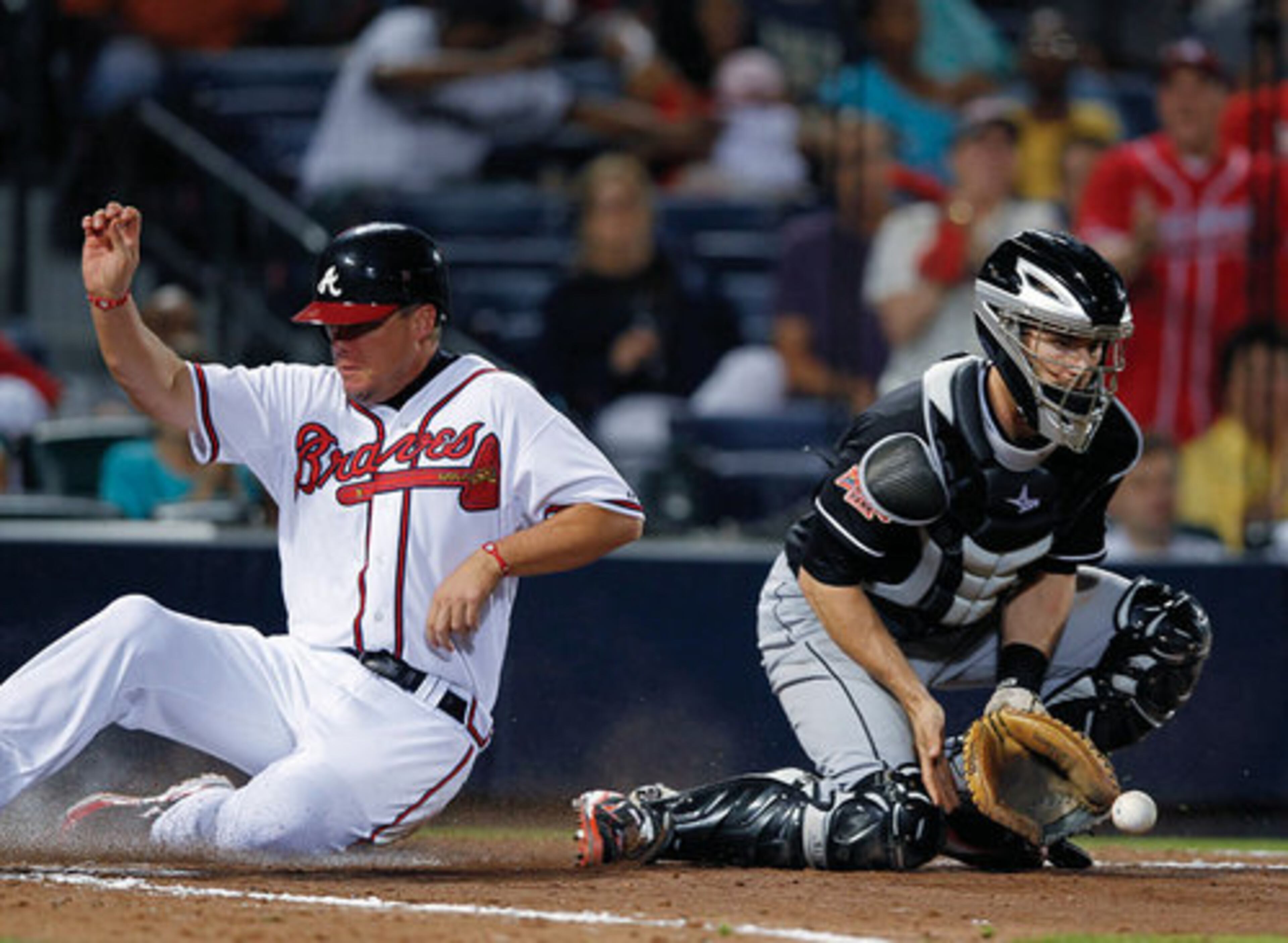 Chipper Jones scores on a Brandon Beachy base hit as Miami Marlins catcher Brett Hayes (9) handles the throw in the fifth inning of a baseball game on May 17, 2012, at Turner Field.