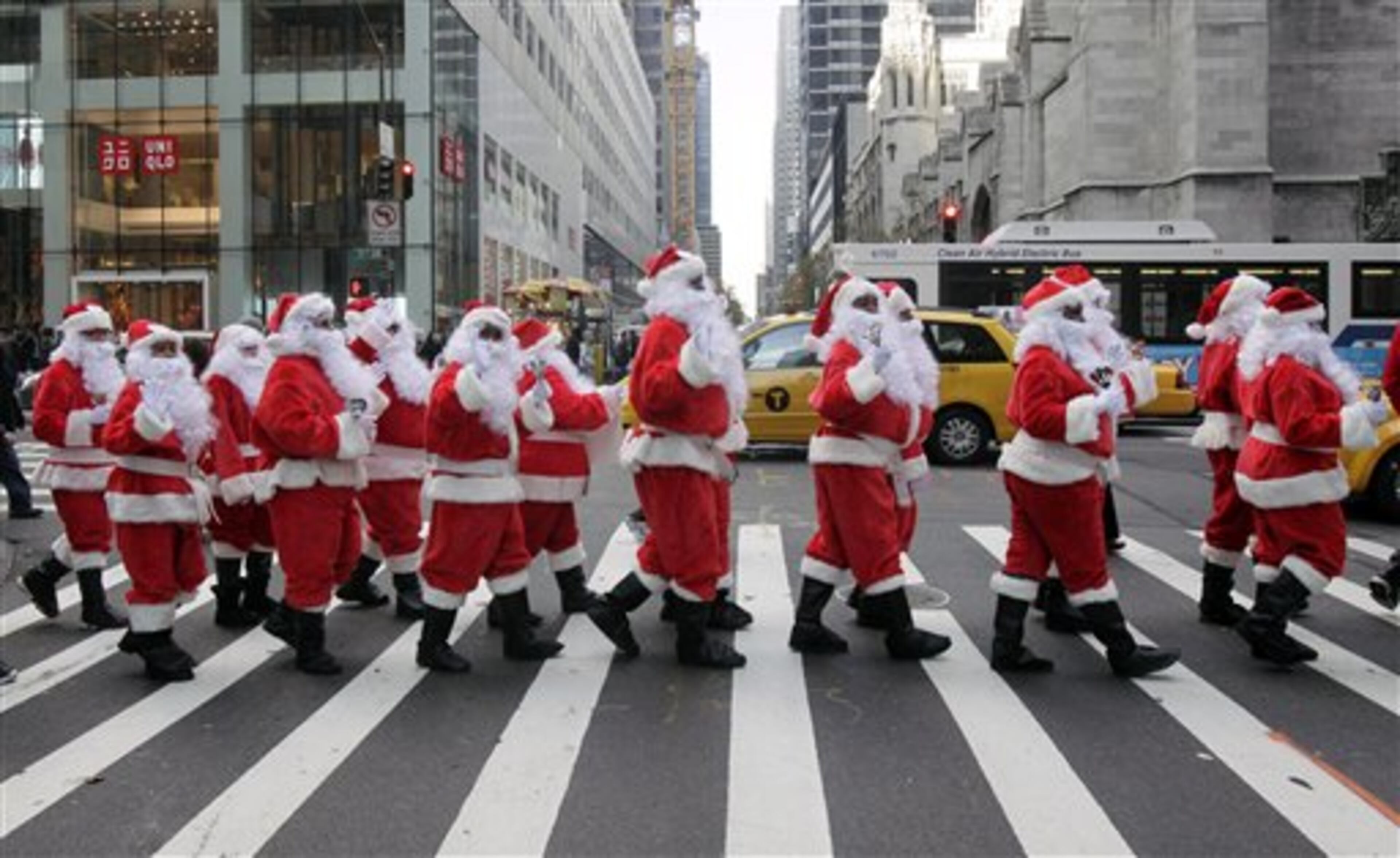 Volunteers of America Santas ring their bells as the cross a street in Fifth Ave. during their 110th annual Sidewalk Santa Parade, in New York, Friday, Nov. 23, 2012. The donations they raise are used for a holiday food voucher program for needy residents. (AP Photo/Richard Drew)