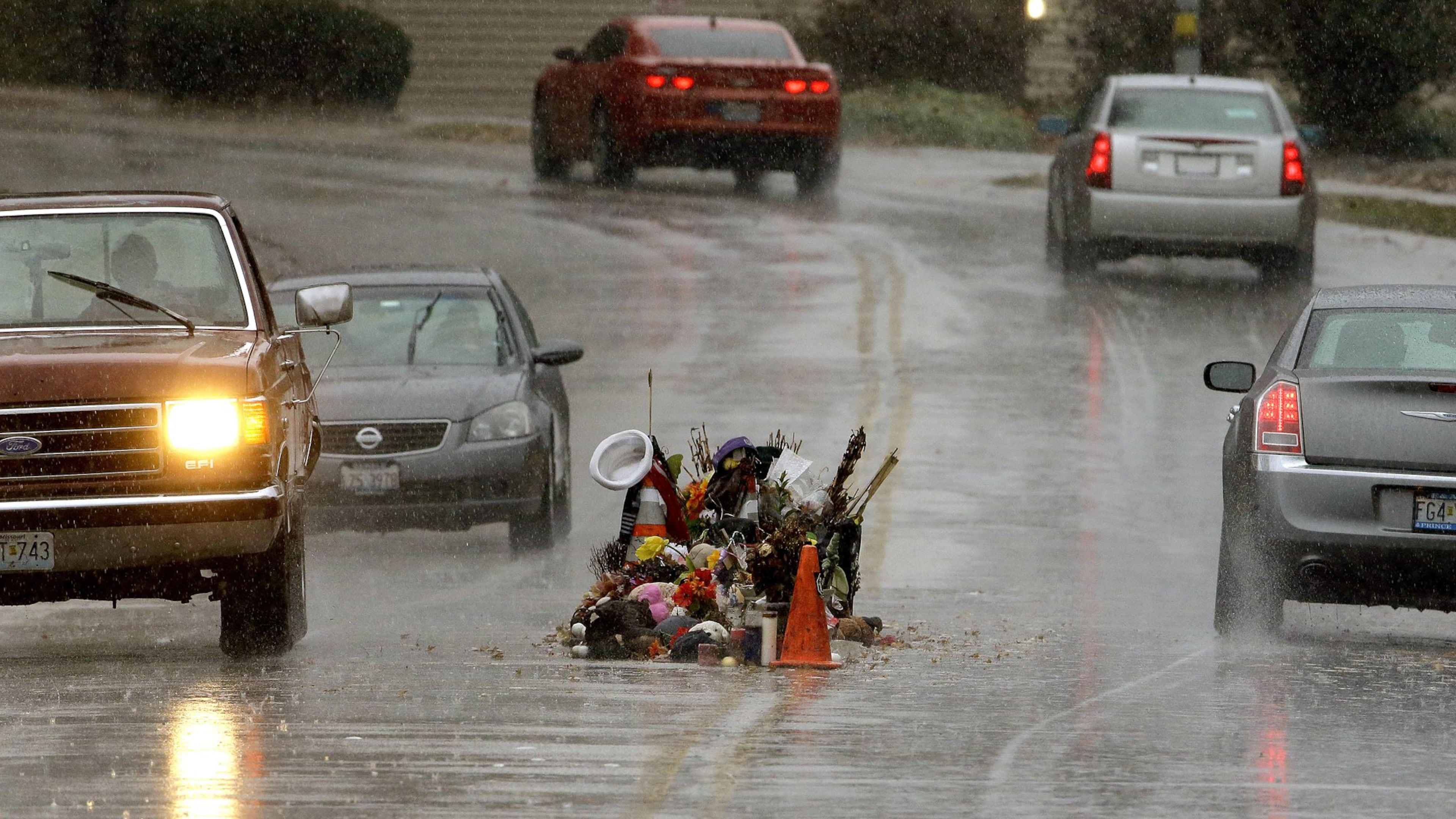 Cars drive past a memorial in the middle of the street this past weekend, more than three months after a black 18-year-old was shot and killed there by a white policeman in Ferguson, Mo. AP / Charlie Riedel