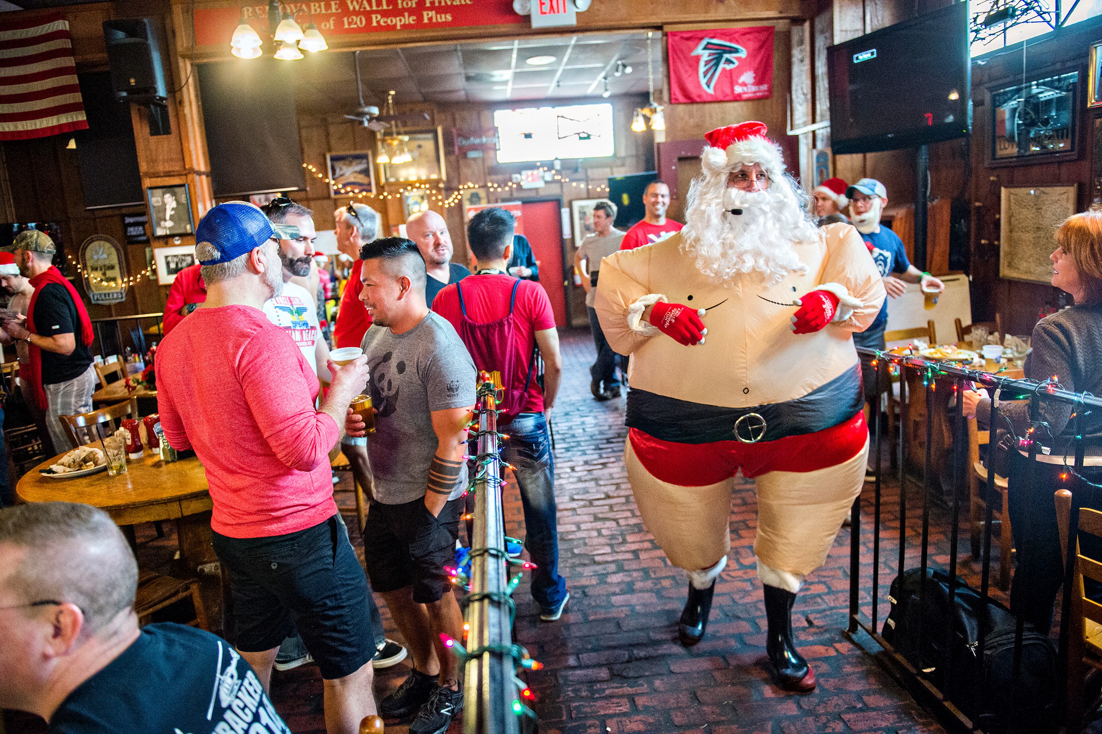 December 12, 2015 Atlanta - Dressed as Santa, Sean Dixon-Parker (right) leads people outside for the start of the annual Atlanta Santa Speedo Run at Manuel's Tavern in Atlanta on Saturday, December 12, 2015. The seventh annual fun run raised over $42,000 for BlazeSports. JONATHAN PHILLIPS / SPECIAL