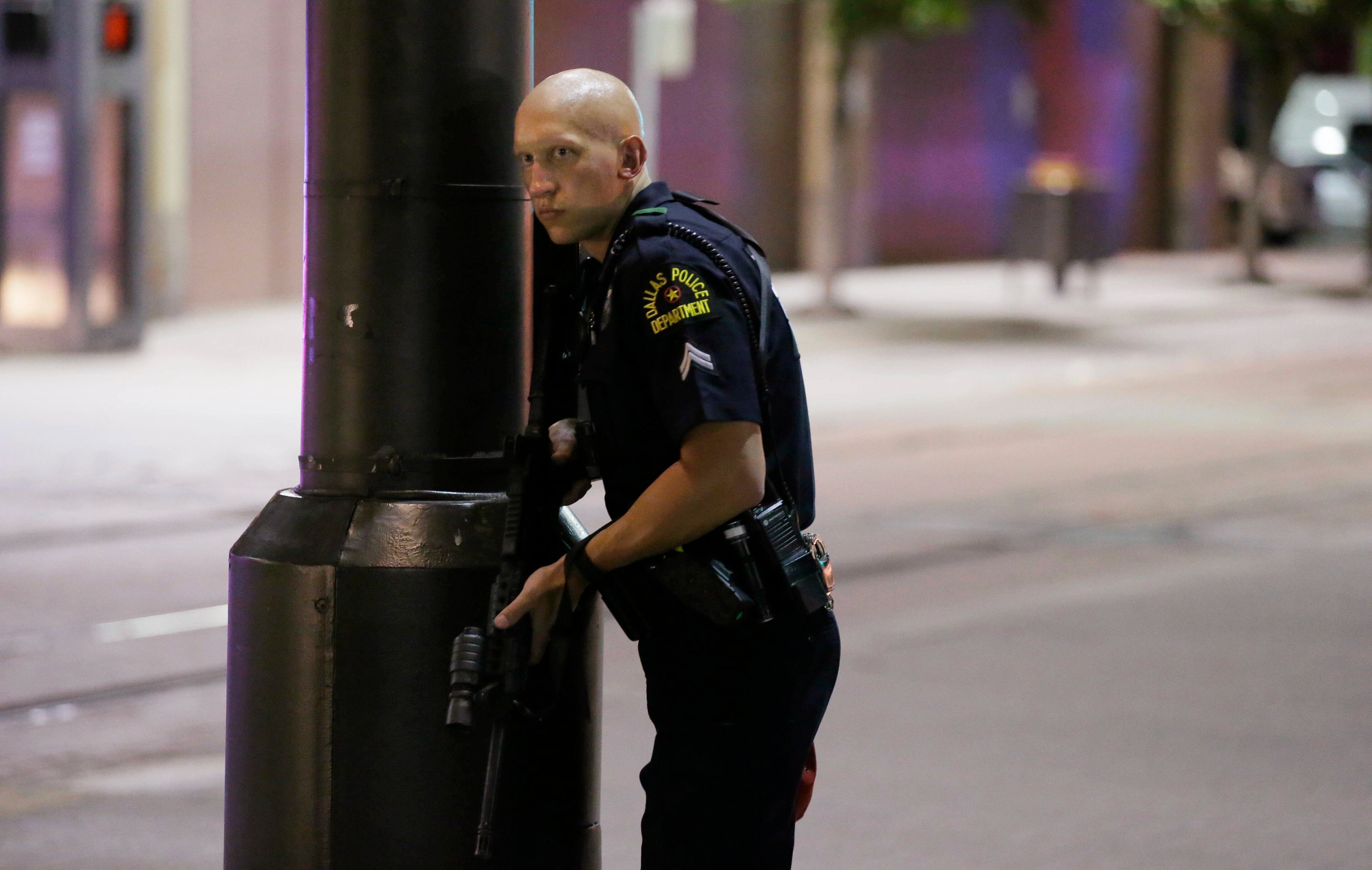 A Dallas policeman keeps watch on a street in downtown Dallas, Thursday, July 7, 2016, following reports that shots were fired during a protest over two recent fatal police shootings of black men. (AP Photo/LM Otero)