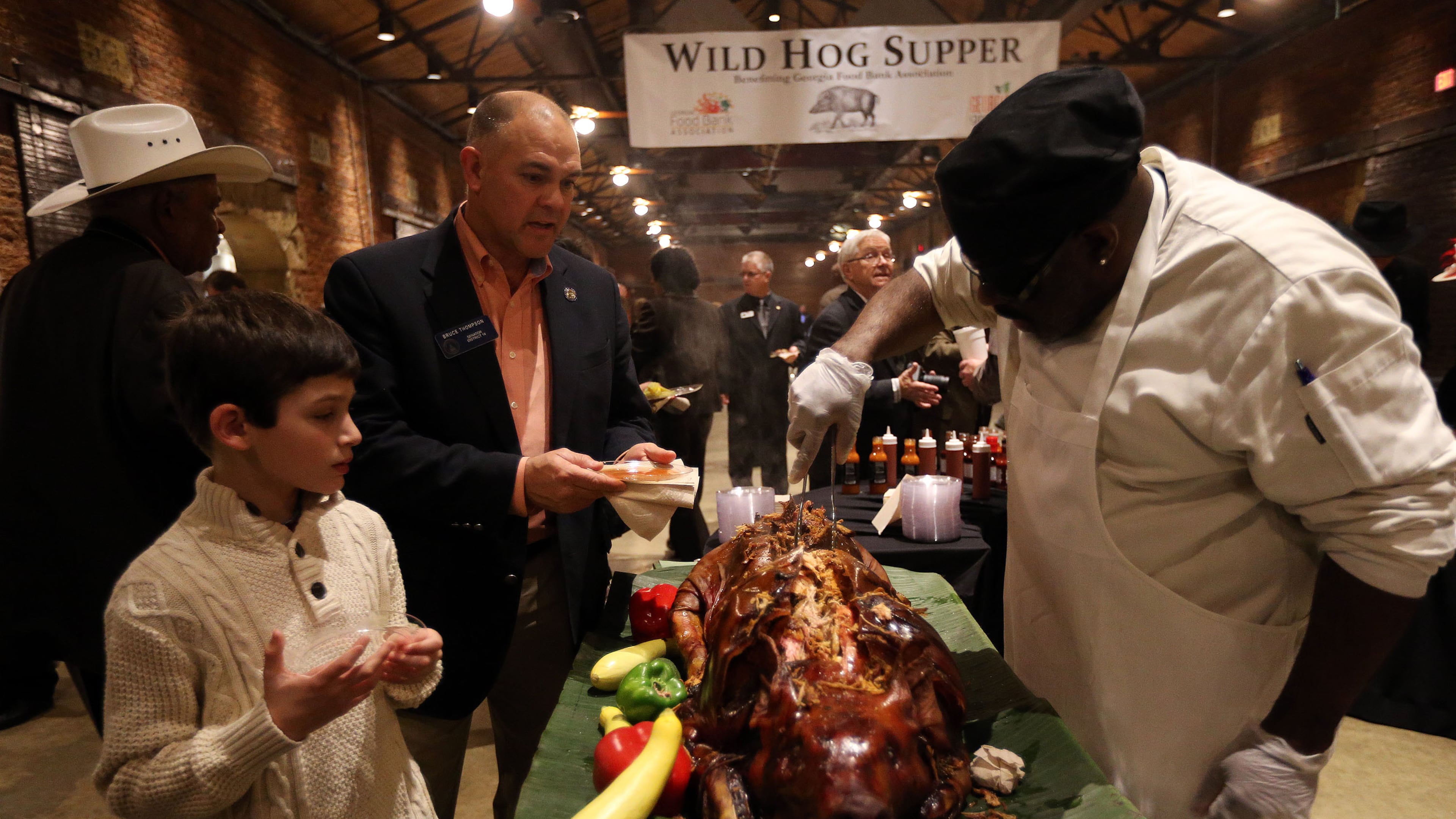 Chef Michel Penton serves up pork to state Sen. Bruce Thompson, R-White, and his son Max during the 53rd annual Wild Hog Supper in January 2015. The supper, the traditional kickoff to the legislative session, has been rescheduled for Feb. 27 after the threat of bad weather canceled it earlier this month. BEN GRAY / BGRAY@AJC.COM