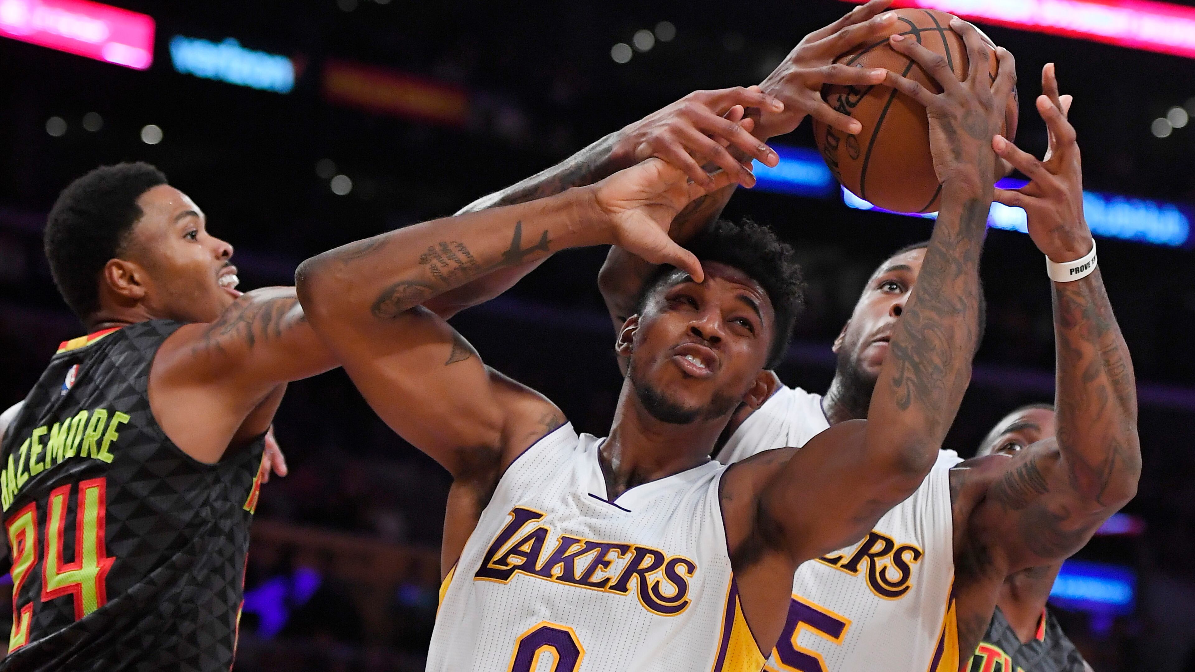 Atlanta Hawks forward Kent Bazemore, left, battles for a rebound with Los Angeles Lakers guard Nick Young, center, and forward Thomas Robinson during the first half of an NBA basketball game Sunday, Nov. 27, 2016, in Los Angeles. (AP Photo/Mark J. Terrill)