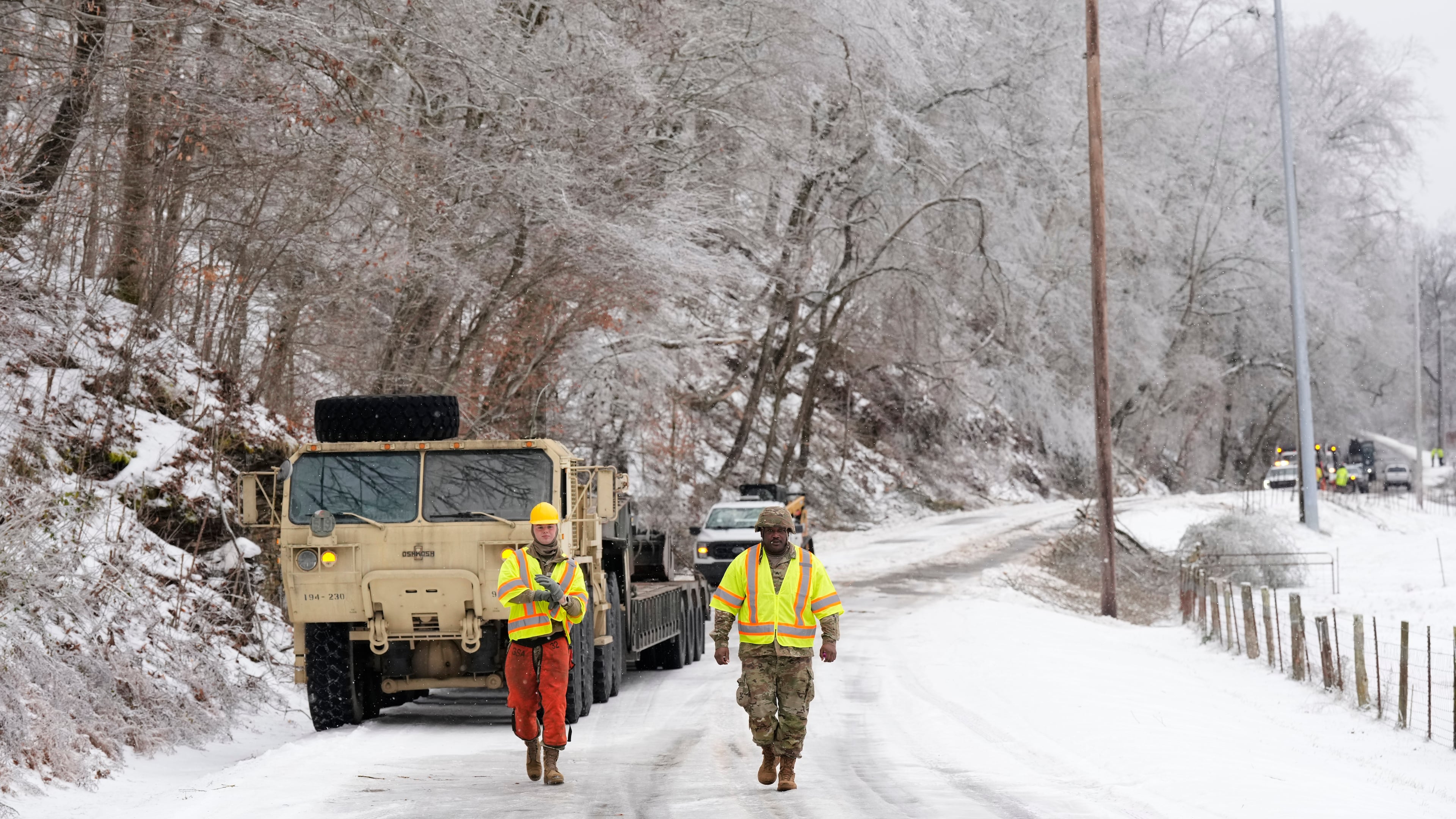 Tennessee National Guard members Taylor Osteen, left, and Antuwan Powell walk along an ice covered road as they work to remove trees Friday, Jan. 30, 2026, in Nashville, Tenn. (AP Photo/George Walker IV)
