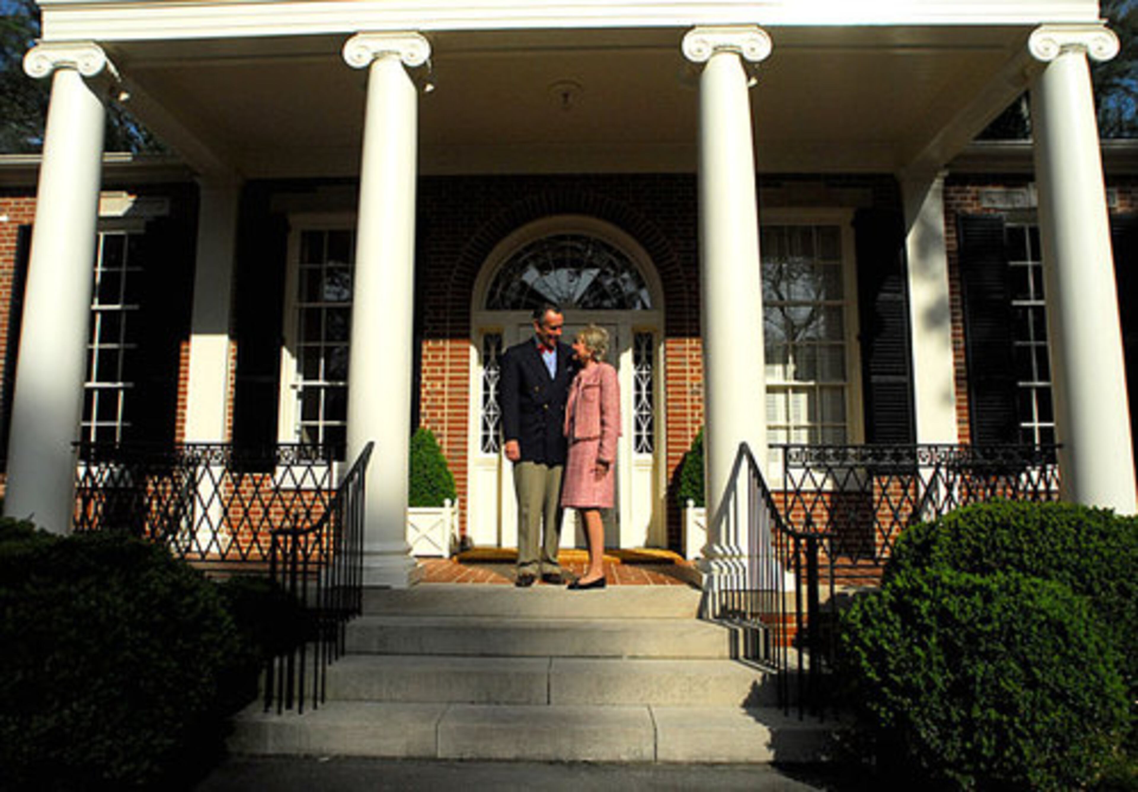 Robbie and Anne Colgin stand in front of their Buckhead home, which is known as Tusquitee. Lewis "Buck" Crook of Ivey and Crook designed the Southern classical revival style house in 1952. Ionic columns add to the Greek influence, and the red brick and portico show evidence of a Jeffersonian influence.
