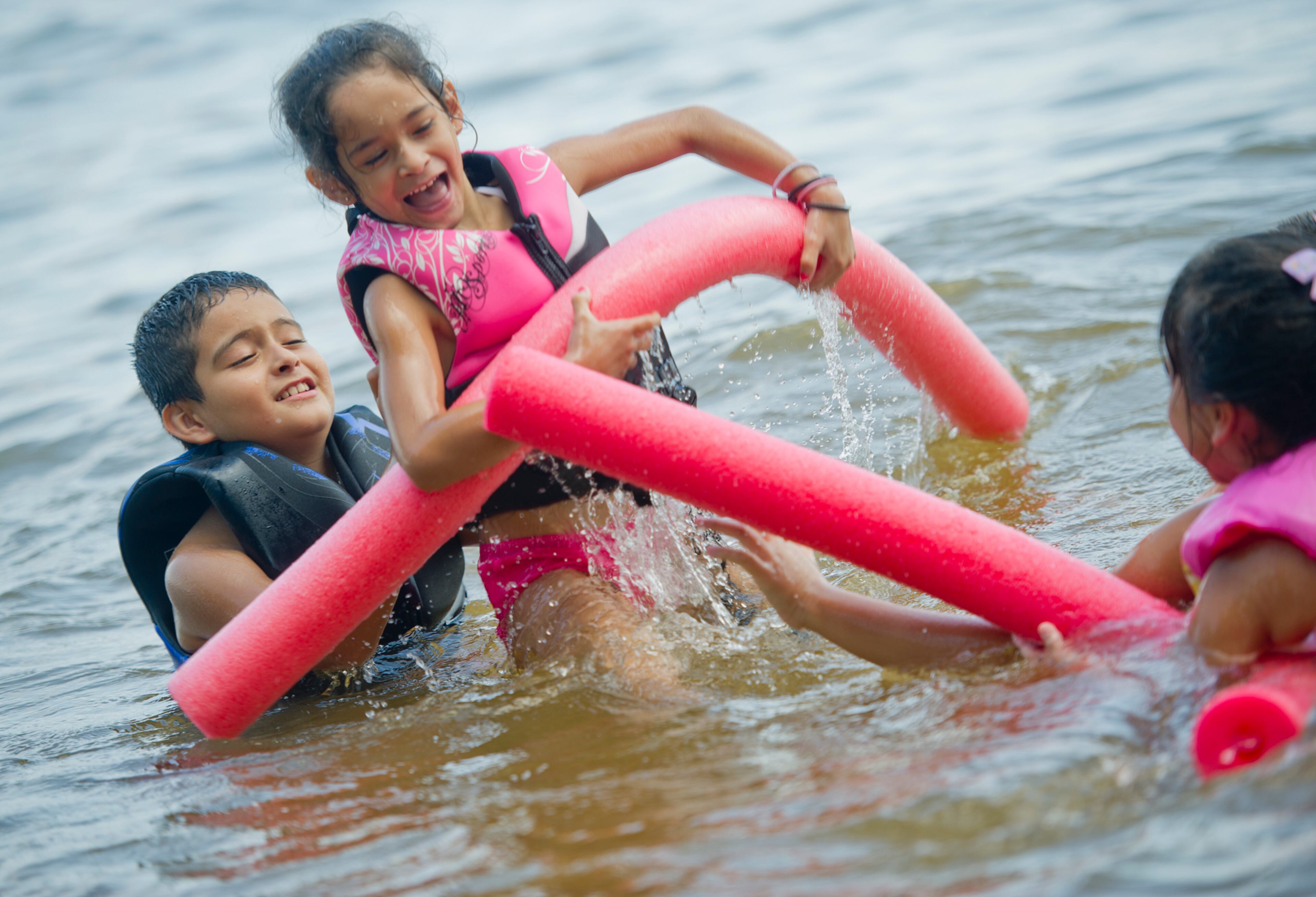 Rodrigo Hernandez (left) lifts his sister, Michelle, into the air as they swim in Lake Lanier at Van Pugh Park.