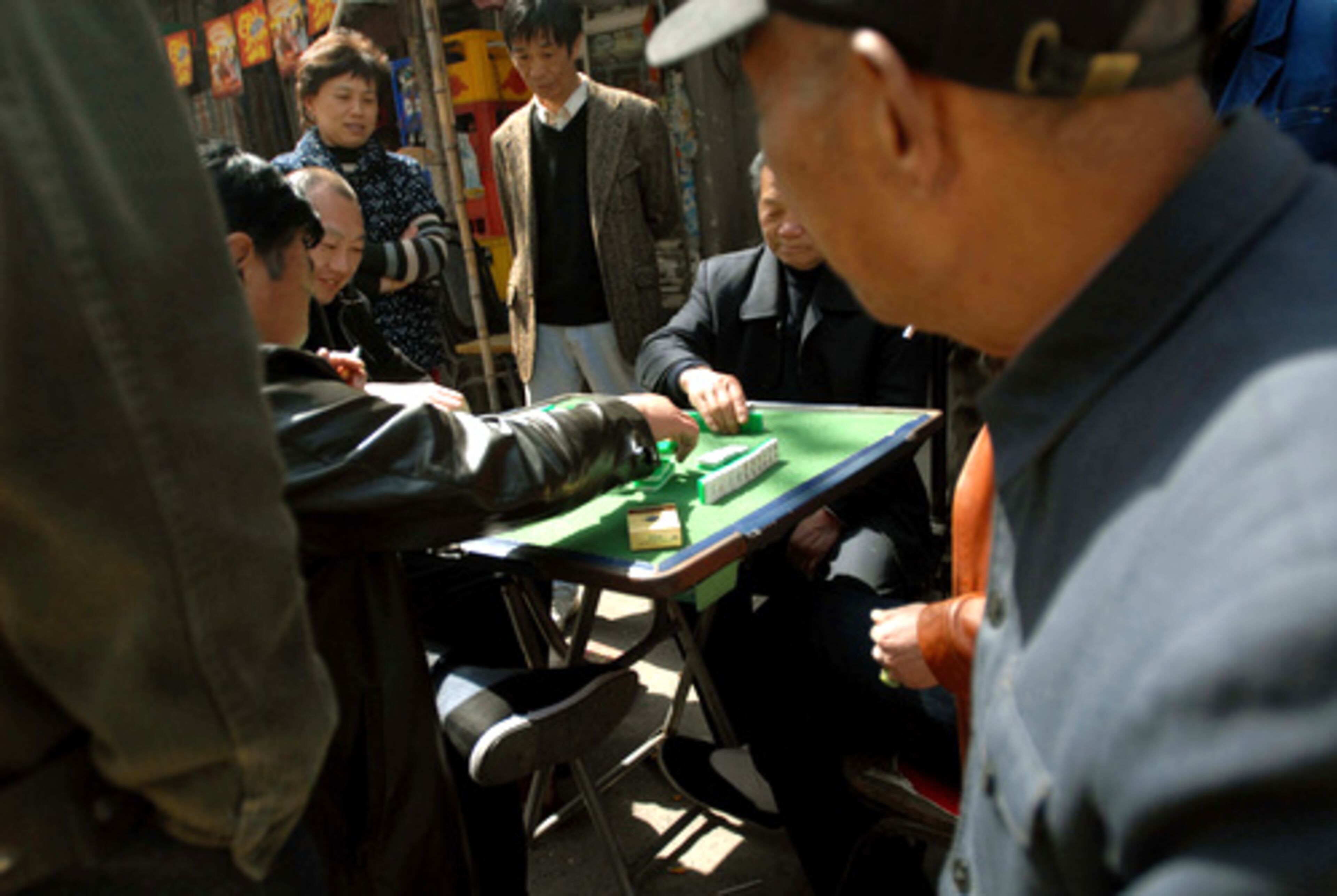 A crowd watches men playing mahjong on Shanghai's Dongtai Road.