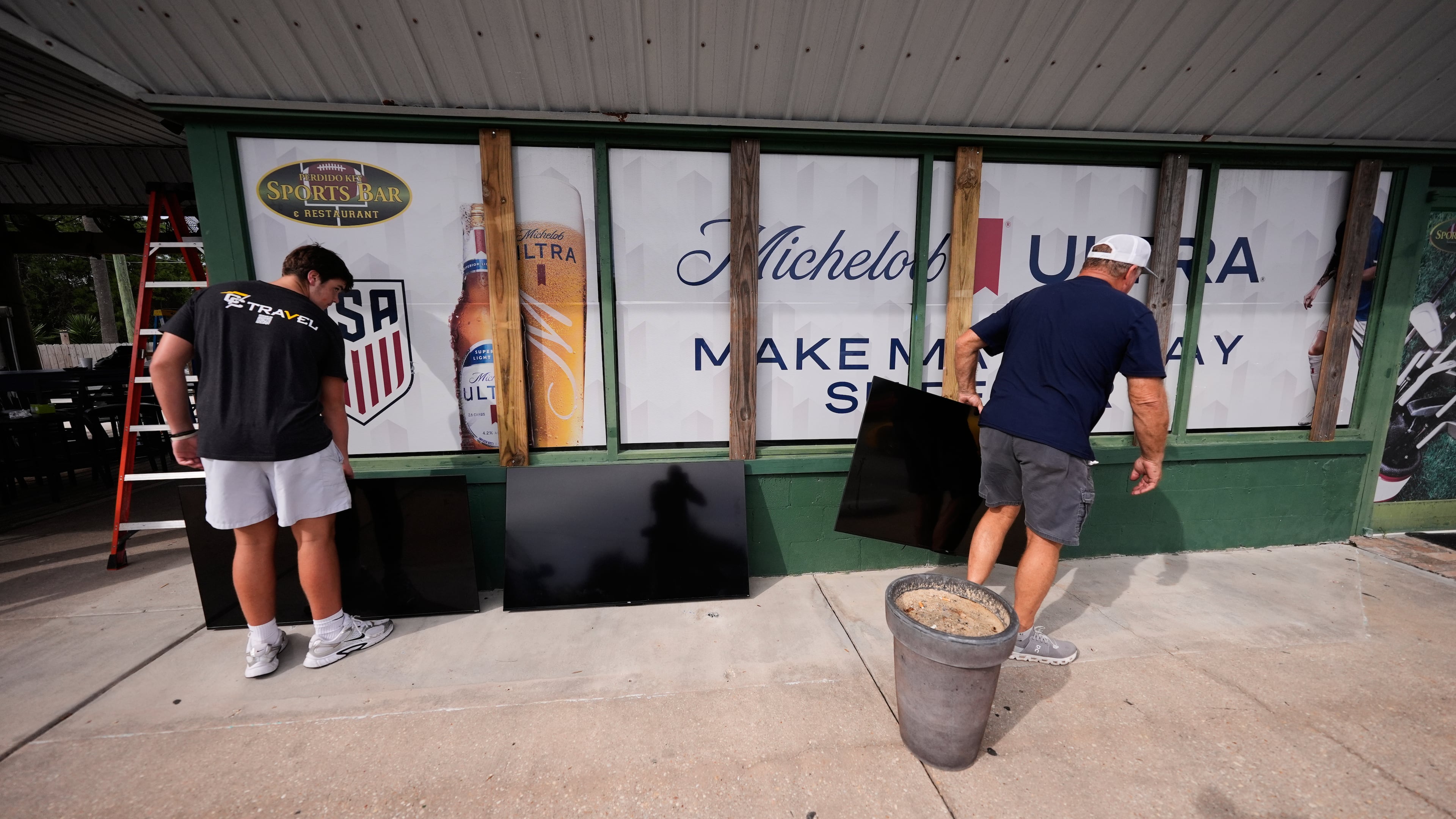Lexington Brown (left) and Mike Howard remove TVs from the patio of the Perdido Key Sports Bar as Hurricane Isaias approaches Perdido Key, Fla., Thursday, Oct. 8, 2026. (Gerald Herbert/AP)