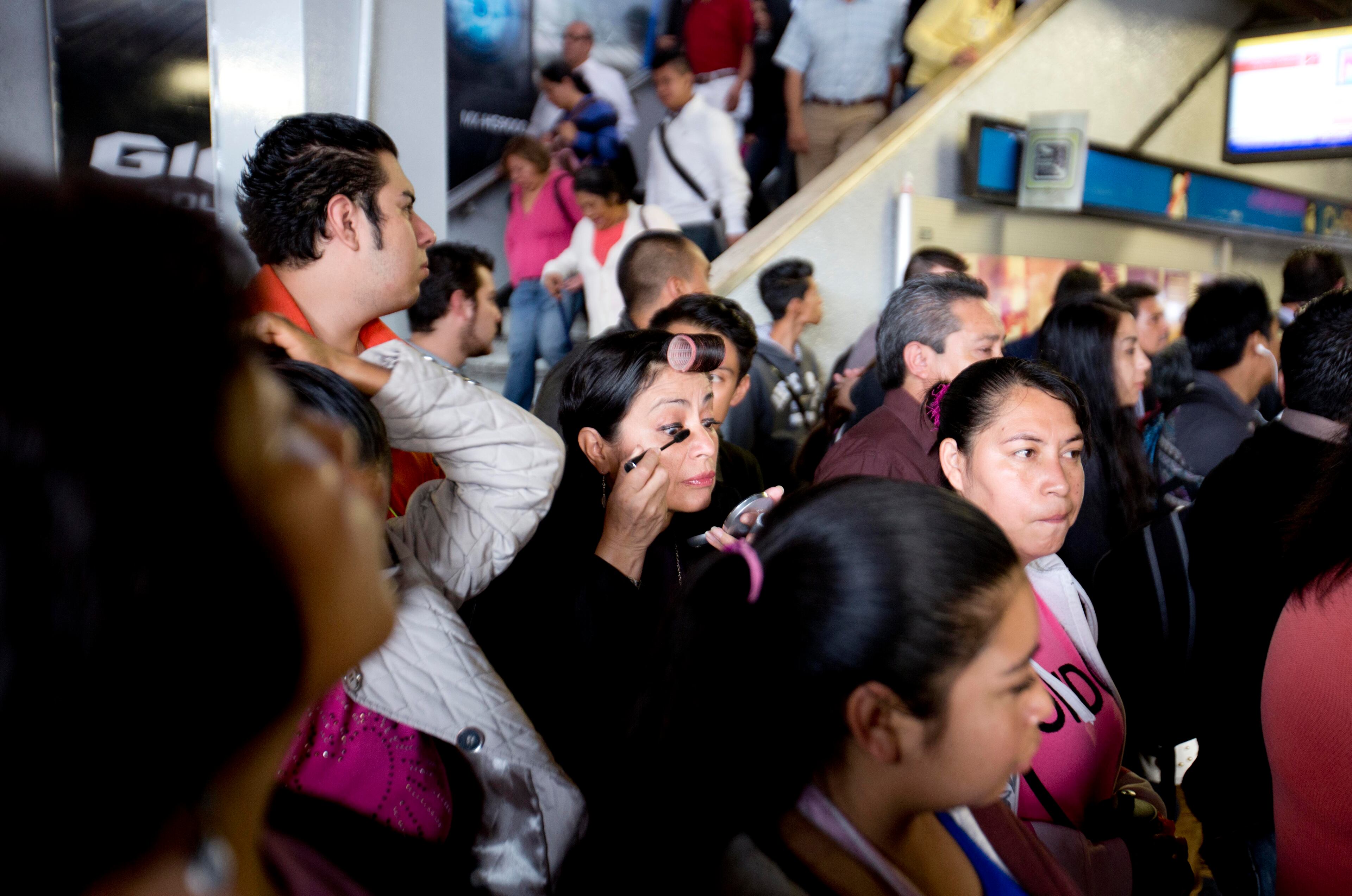 In this Sept. 22, 2014 photo, a passenger wearing a hair roller puts on her makeup while waiting for a subway car during early morning rush hour in Mexico City. (AP Photo/Eduardo Verdugo)