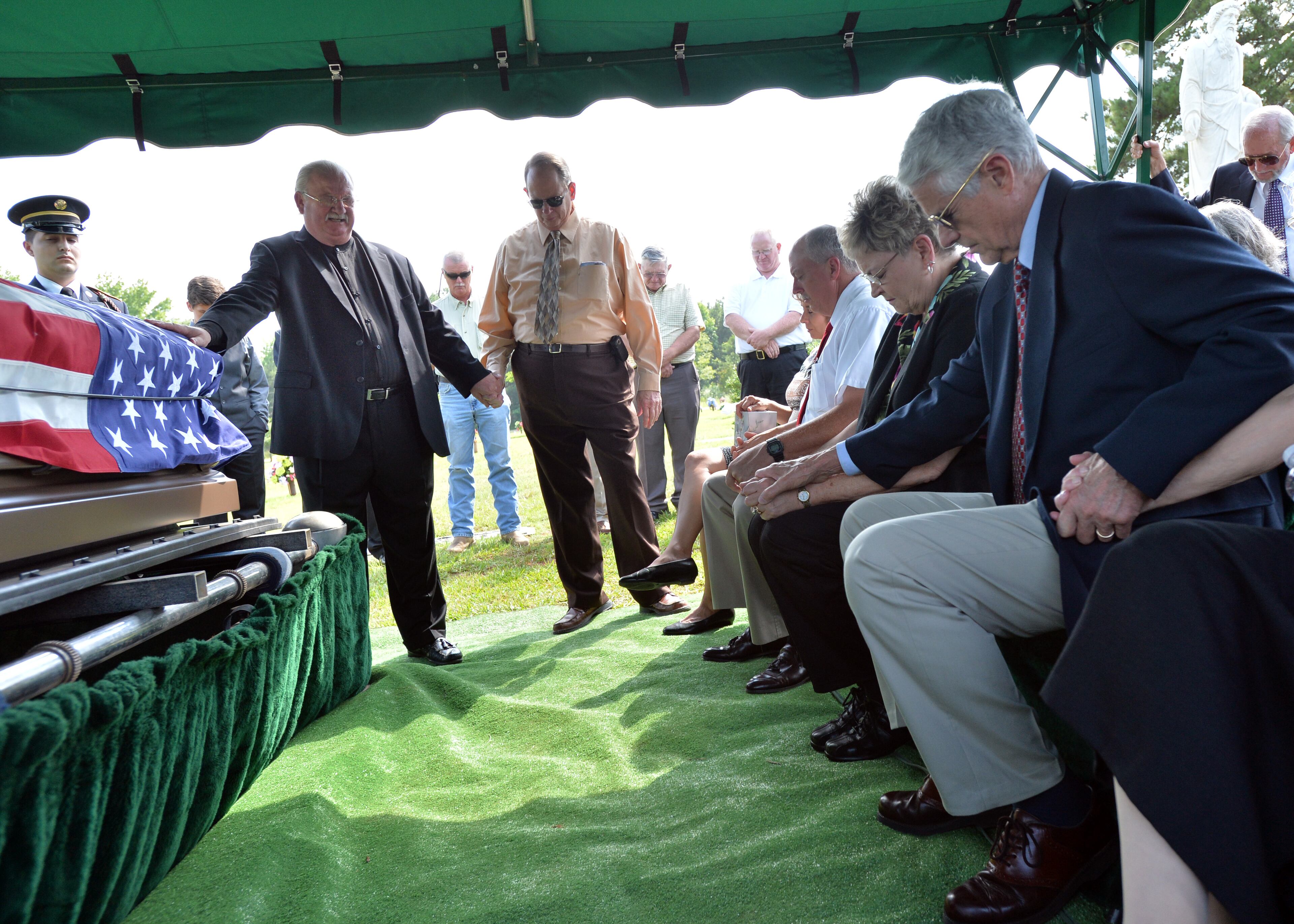 Drucker (left, with hand on casket) leads a prayer as he clasps the hand of Lt. Hal White Jr. during the burial services for White's father, Harry White Sr., at Horis A. Ward Fairview Chapel in Stockbridge.