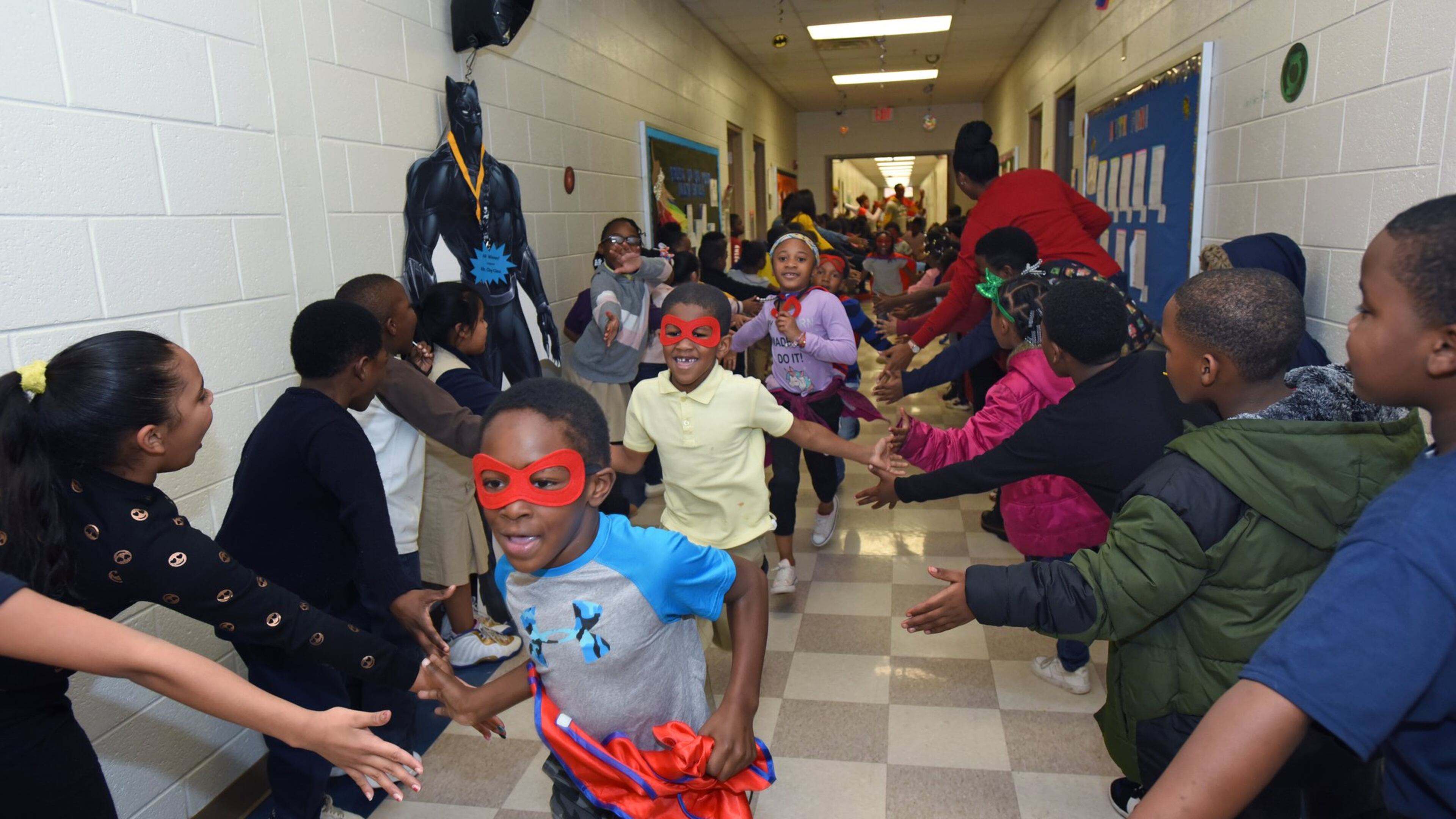 Students participate in the Friday attendance run at Miles Elementary School on Friday, Nov. 22, 2019. Students with good attendance get to run around the hallways dressed up in capes and masks as superheroes. (AJC FILE).
