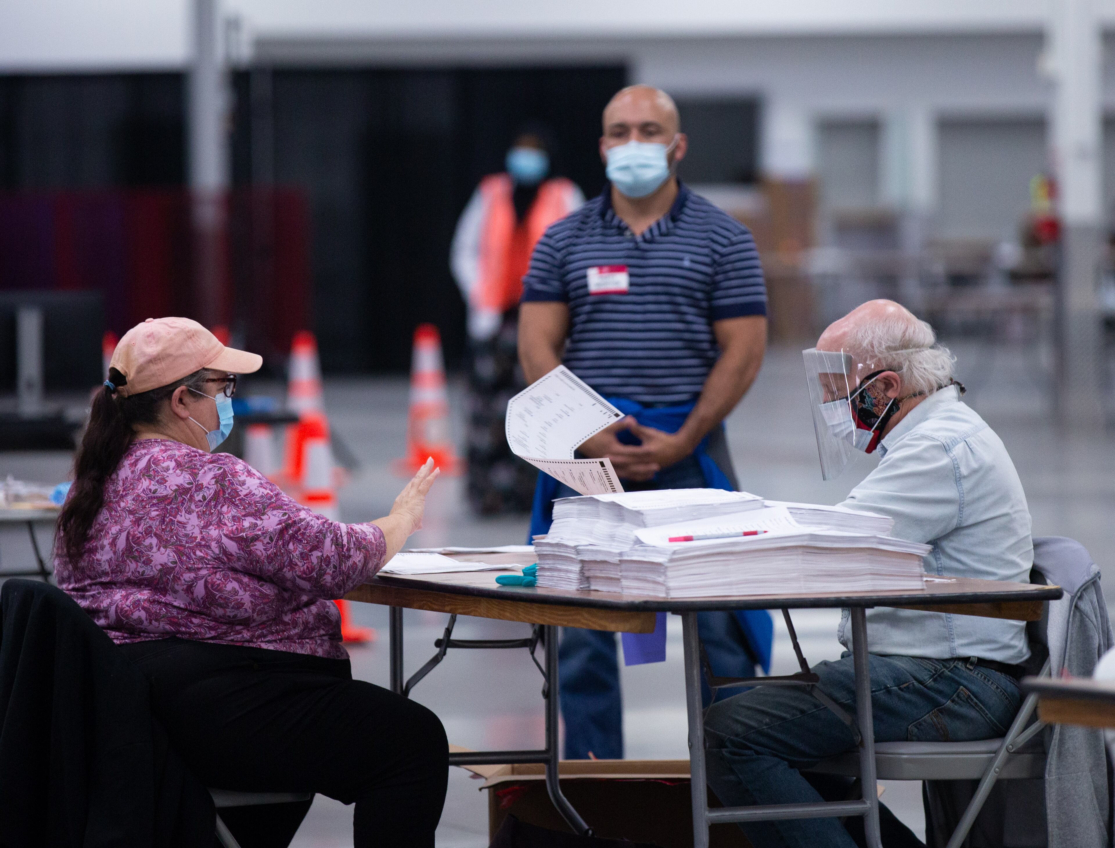 A party observer watches as people recount ballots from the 2020 presidential election on Sunday, Nov. 15, 2020, in Stonecrest. (Rebecca Wright for the Atlanta Journal-Constitution)