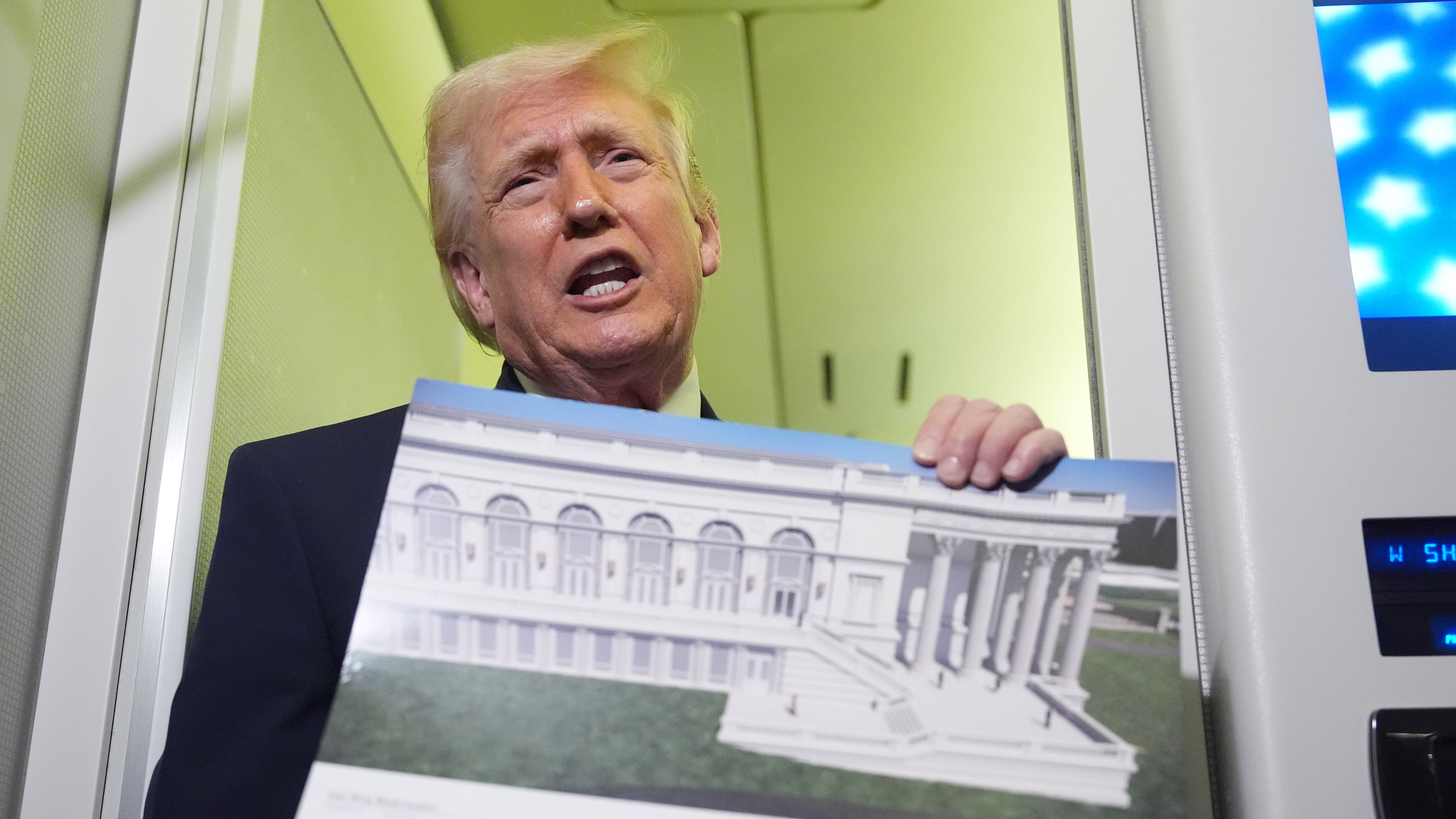 President Donald Trump holds a rendering of the proposed new East Wing of the White House as he speaks to reporters aboard Air Force One en route from West Palm Beach, Fla., to Joint Base Andrews, Md., Sunday, March 29, 2026. (AP Photo/Mark Schiefelbein)