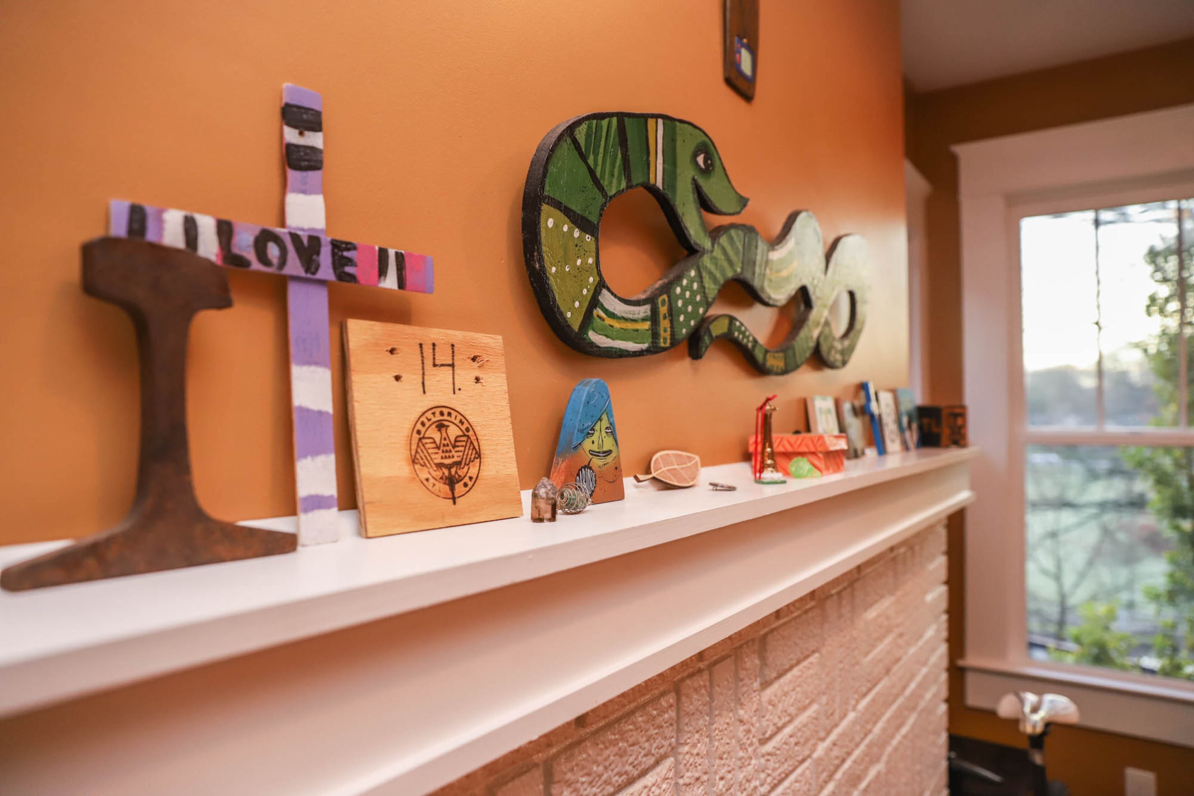 Local art, including pieces by Kyle Brooks and artists known as Evereman and Catlanta, lines the mantel in the living room.