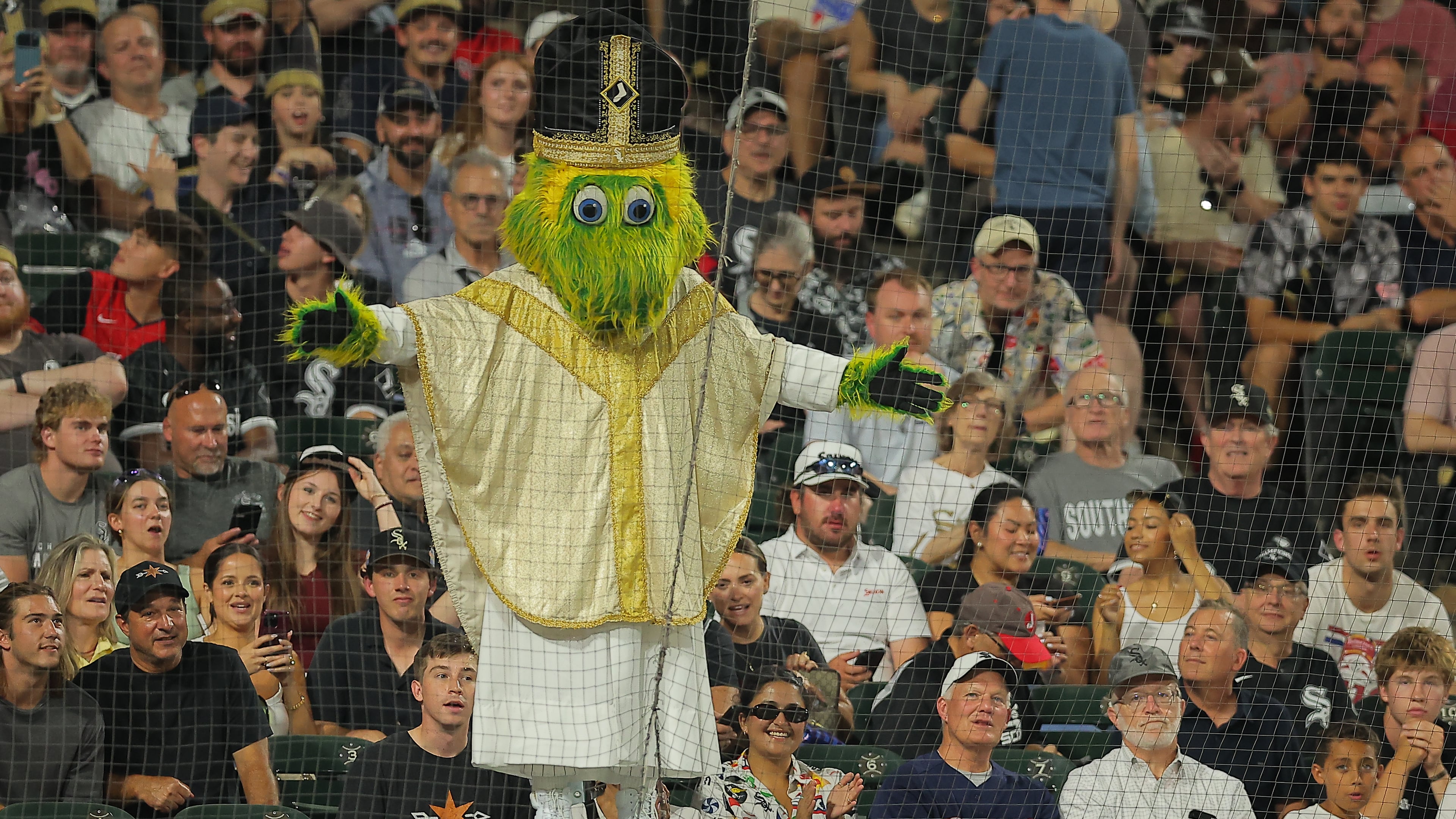 Chicago White Sox mascot Southpaw stands on the dugout wearing a pope outfit during the seventh inning of a baseball game against the Cincinnati Reds, Tuesday, Aug. 11, 2026, in Chicago. (AP Photo/Melissa Tamez)