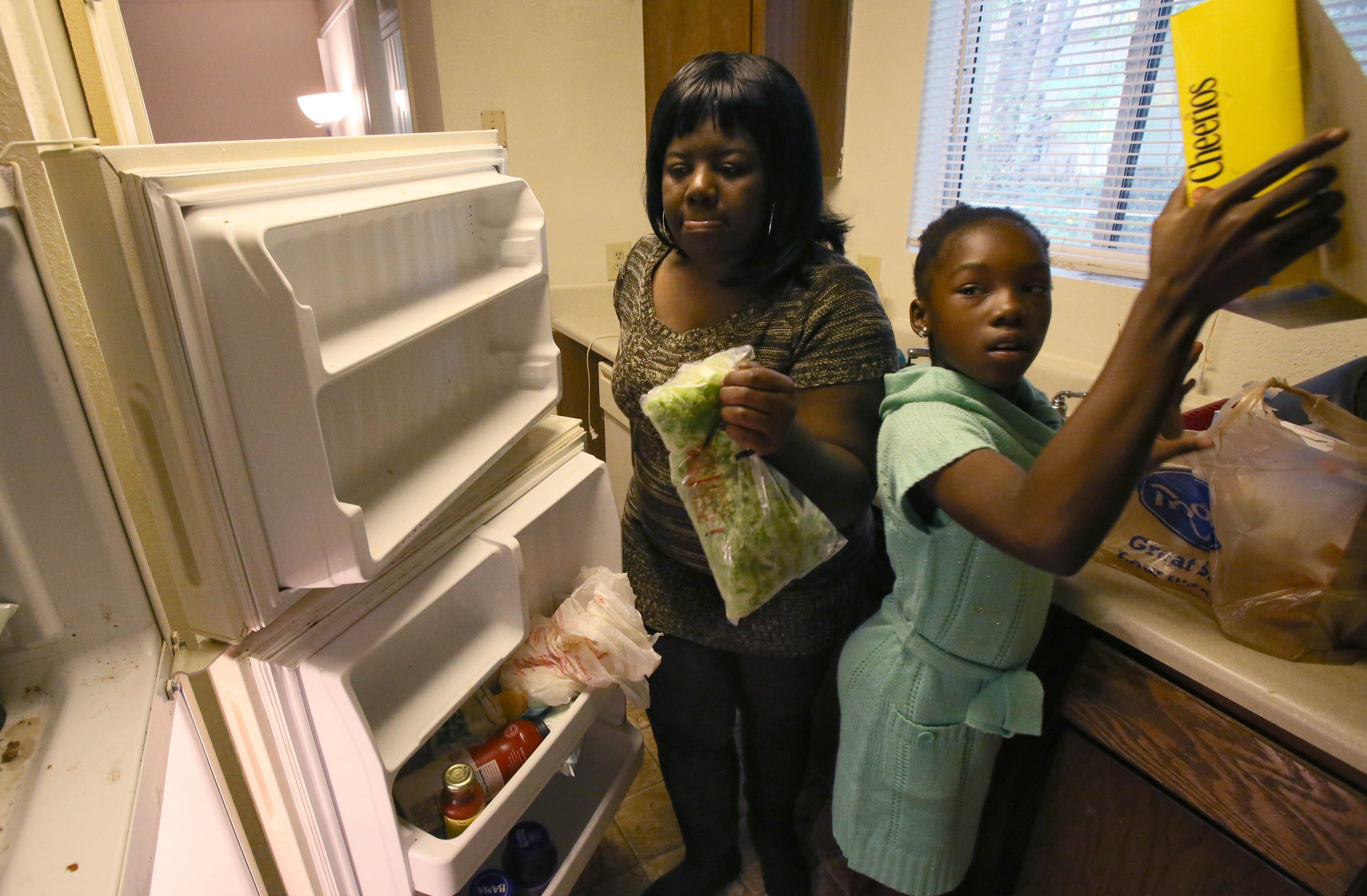 Mikyia Damous, 10, helps her mother, Lawanna Damous, unload groceries after a trip to Kroger. BOB ANDRES / BANDRES@AJC.COM