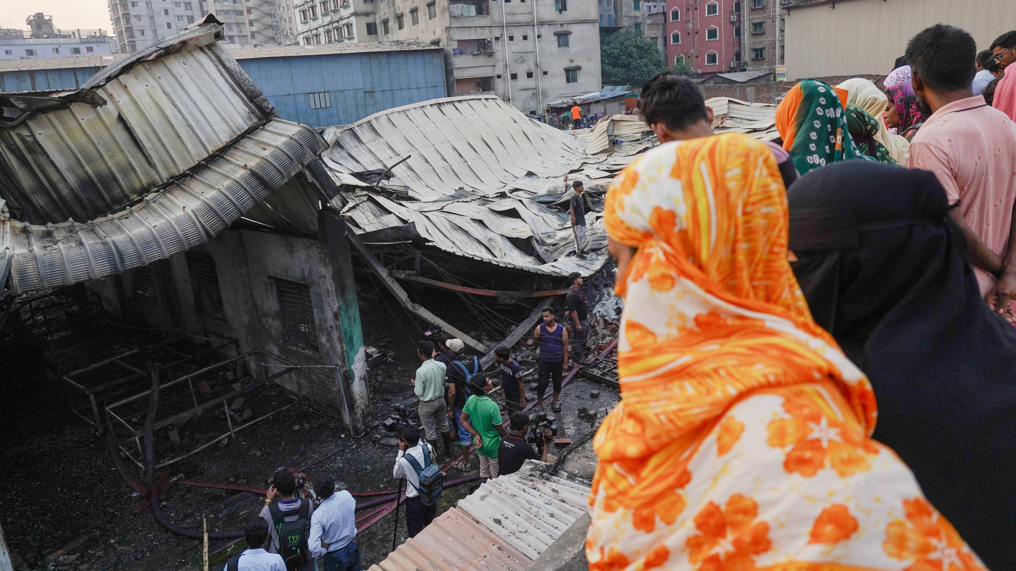 People look at the charred remains of a gas-lighter manufacturing factory in Keraniganj on the outskirts of Dhaka, Bangladesh, Saturday, April 4, 2026. (AP Photo/MD. Samsul Islam Hady)