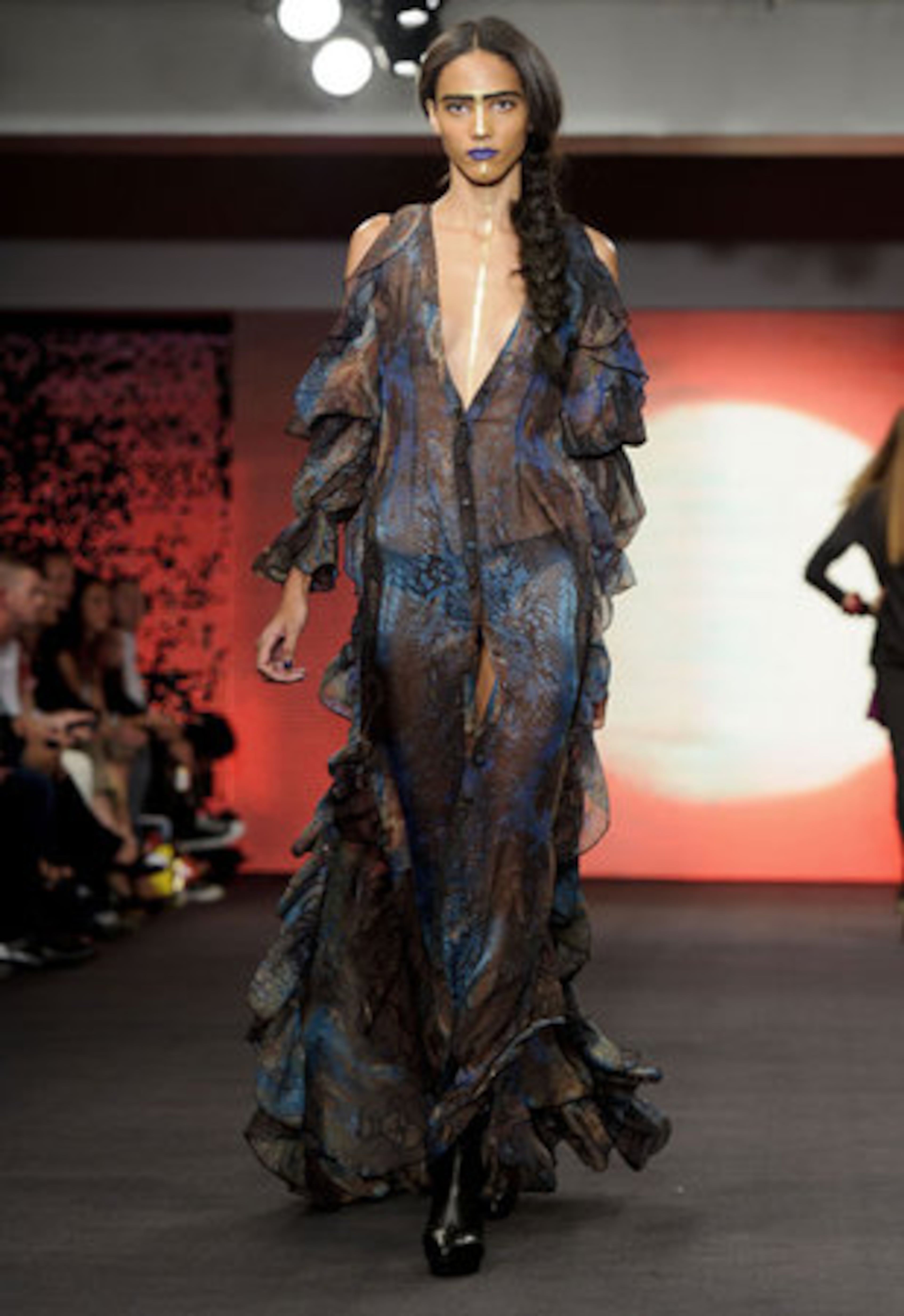 A long, sheer gown is presented on the runway.