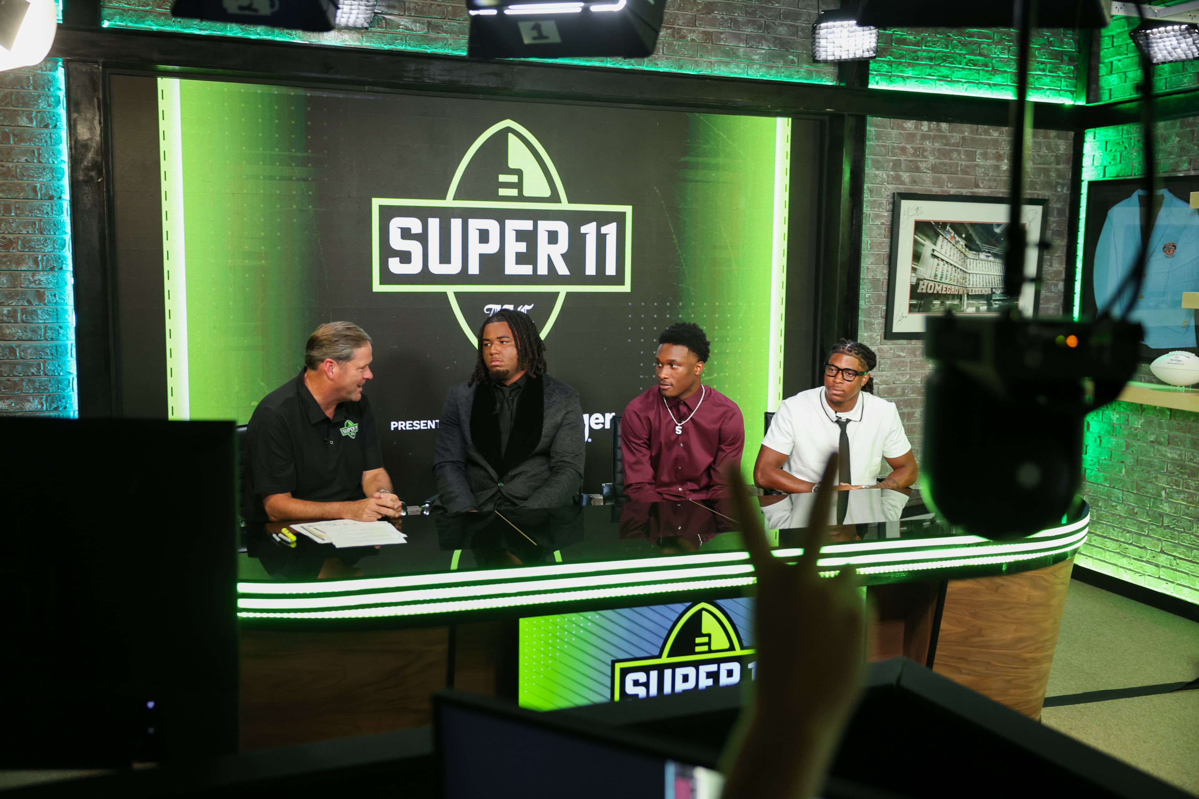 (L-R) DawgNation’s Brandon Adams interviews Northside’s Elijah Patmon, Lee County’s Jaden Upshaw and Howard’s Ta'Shawn Poole during the taping of the Super 11 reveal show at Score ATL in Roswell on Aug. 3, 2026. (Arvin Temkar/AJC)
