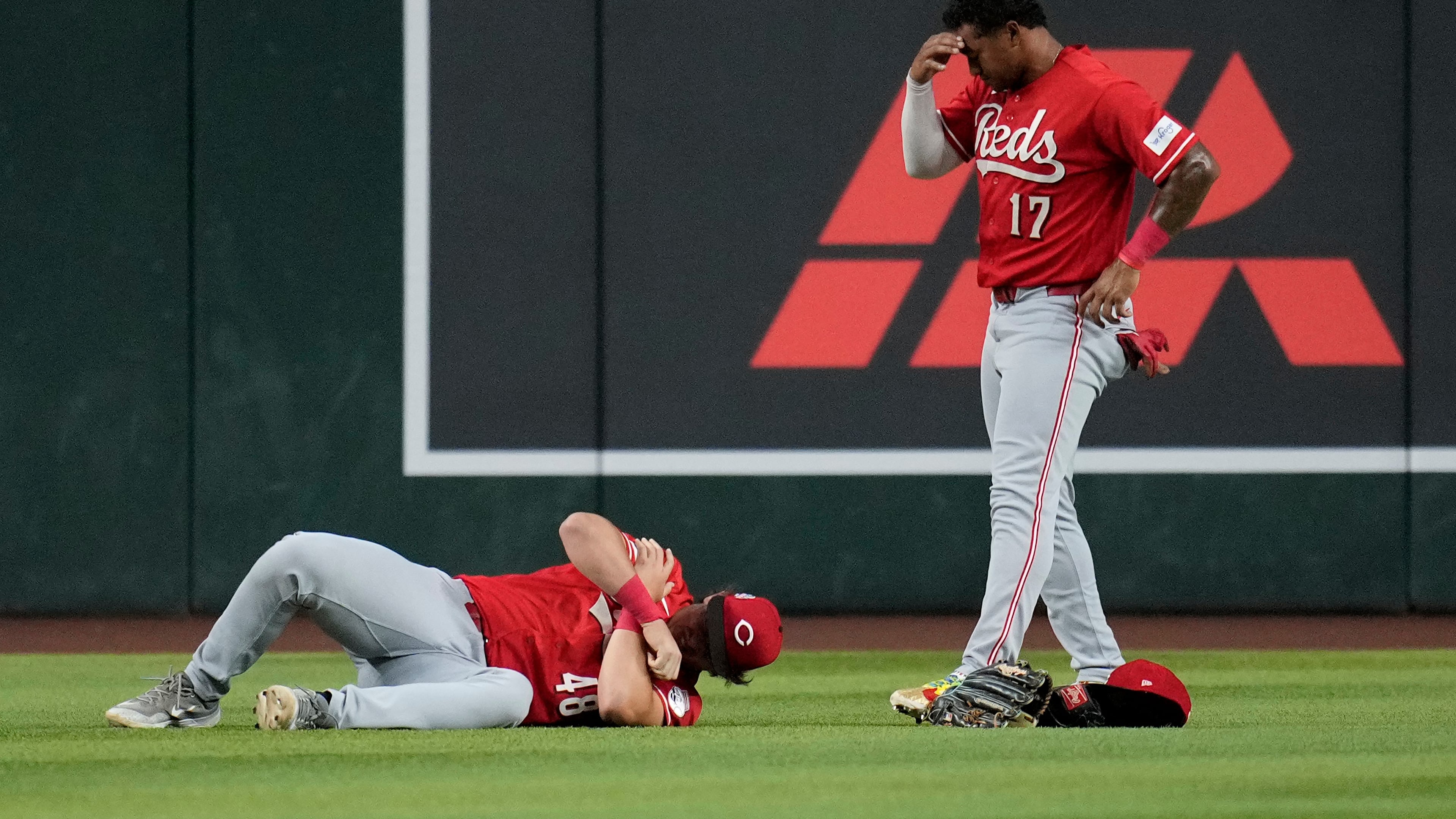An injured Cincinnati Reds left fielder Michael Toglia (48) holds his shoulder as Reds center fielder Dane Myers (17) looks on during the first inning of a baseball game against the Arizona Diamondbacks, Friday, Aug. 21, 2026, in Phoenix. (AP Photo/Ross D. Franklin)