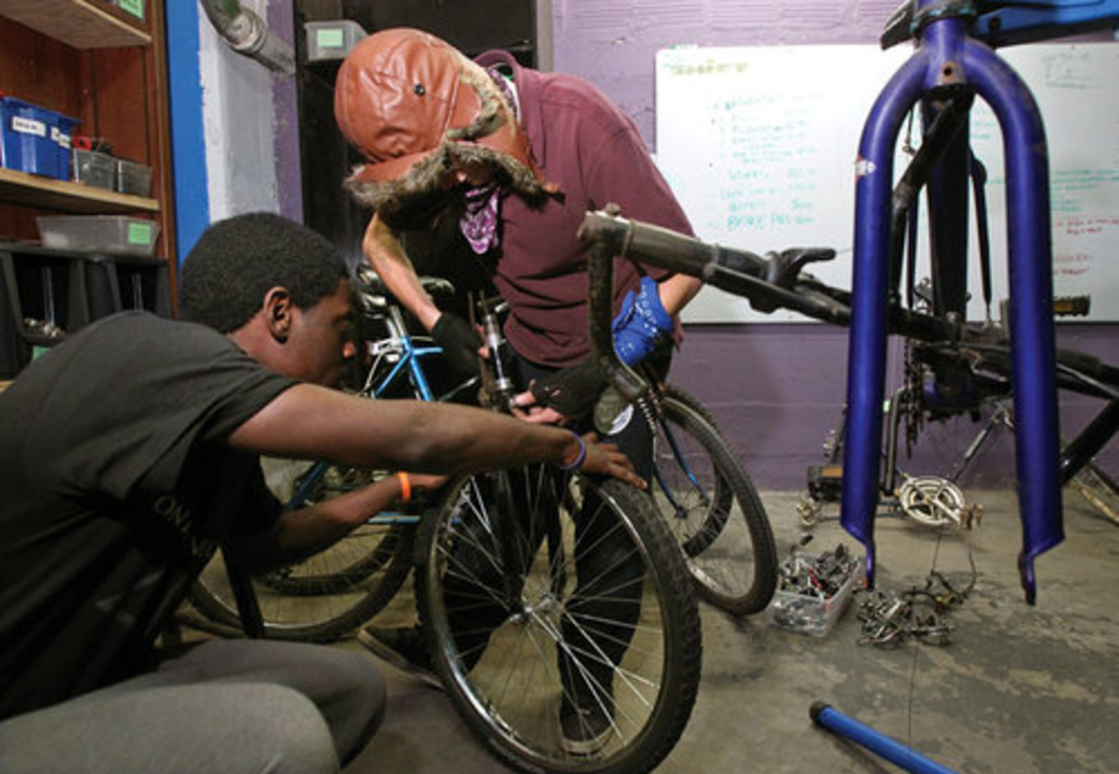 Joshua Hill, 23, left, and Colin Prentice, 18, center, both with Occupy Atlanta, work on repairing a bicycle in the SHIFT bicycle shop at the Metro Atlanta Task Force for the Homeless.in exchange for being allowed to stay at the shelter.