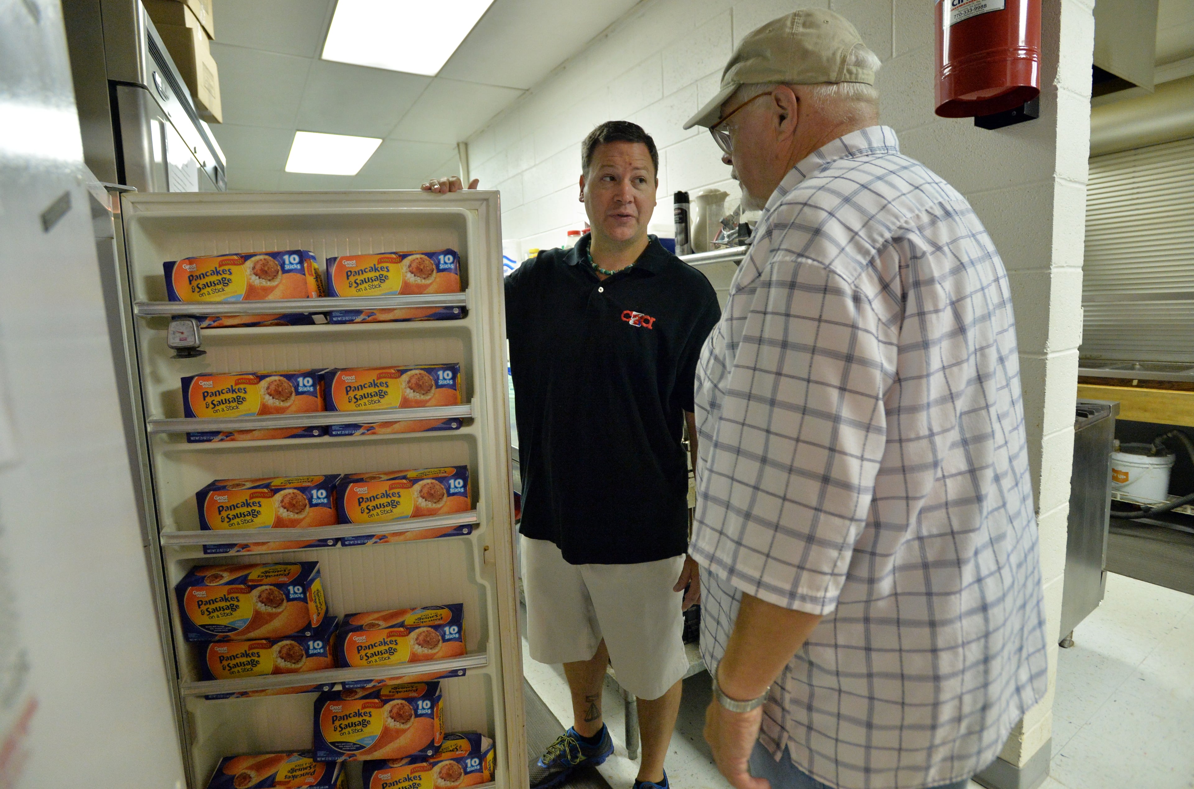 August 9, 2014 Atlanta - Jeremy Turner, executive director of Contribute2America, confers with Lee Caldwell, manager of C2A Food Co-op, as they check food in a refrigerator at Briarcliff United Methodist Church. HYOSUB SHIN / HSHIN@AJC.COM
