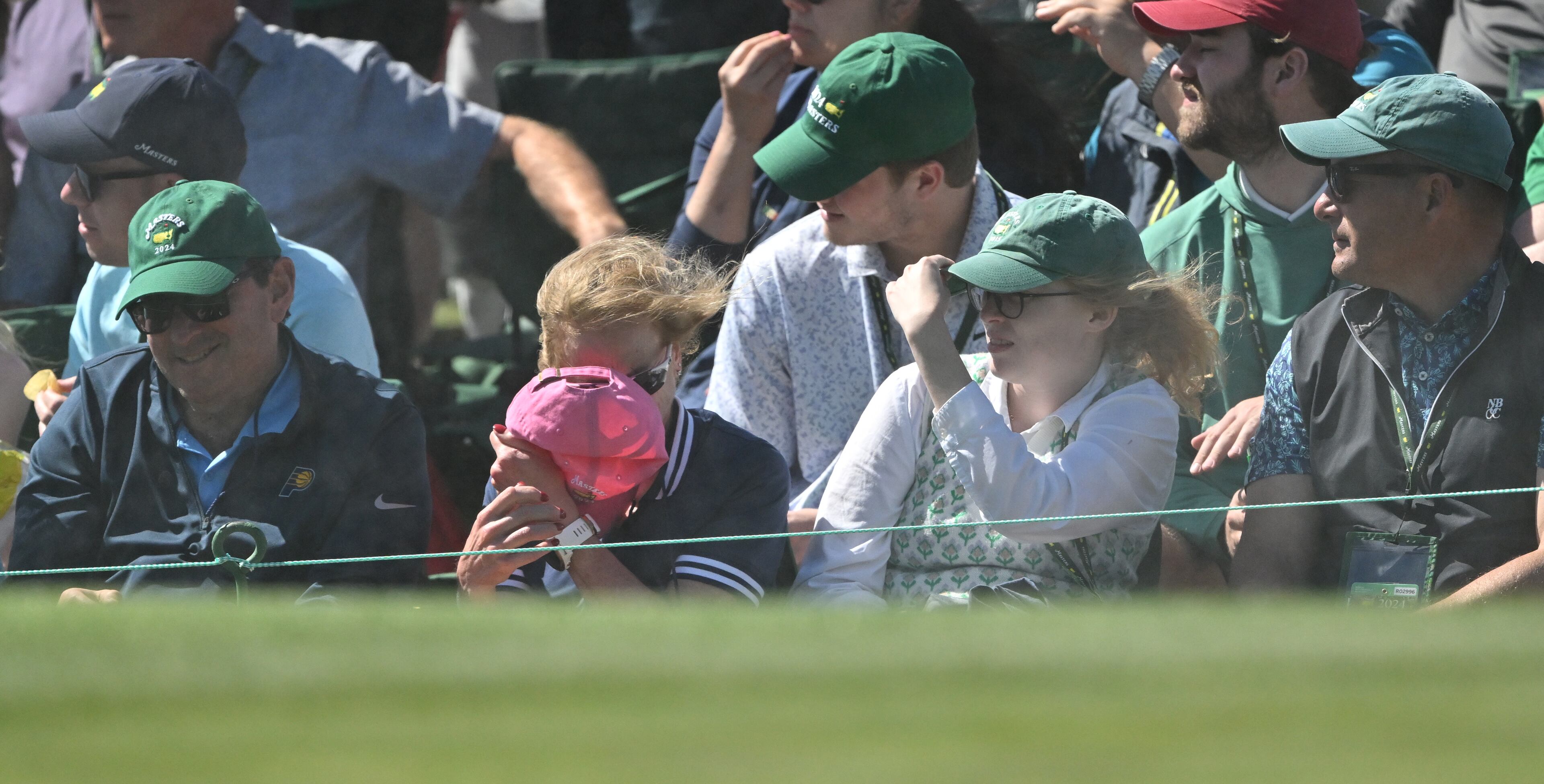 Patrons shield themselves from the wind and blowing sand on 18th green during second round of the 2024 Masters Tournament at Augusta National Golf Club, Friday, April 12, 2024, in Augusta, Ga. (Hyosub Shin / Hyosub.Shin@ajc.com)