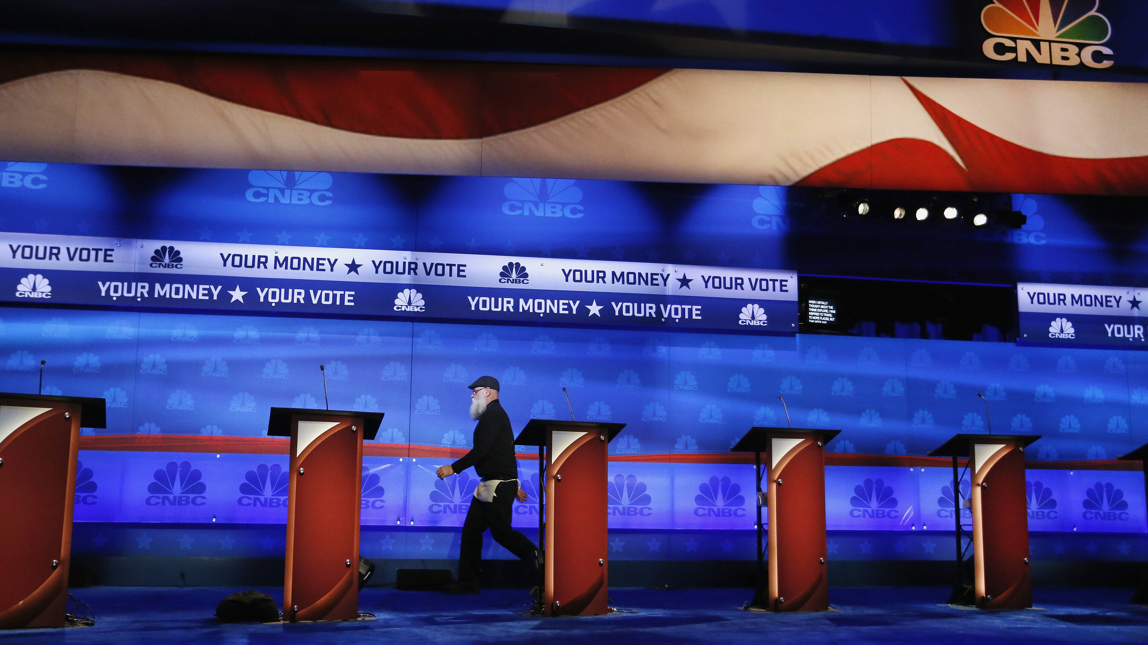 A crew member walks past the candidate podiums at the venue for the Oct. 28 CNBC Republican presidential debate, Tuesday, Oct. 27, 2015, inside the Coors Events Center at the University of Colorado in Boulder, Colo. Republican presidential candidates taking the debate stage Wednesday in Colorado are hoping to carry momentum from a 2014 U.S. Senate victory in this toss-up state where independent voters outnumber the electorate from both major parties. (AP Photo/Brennan Linsley)