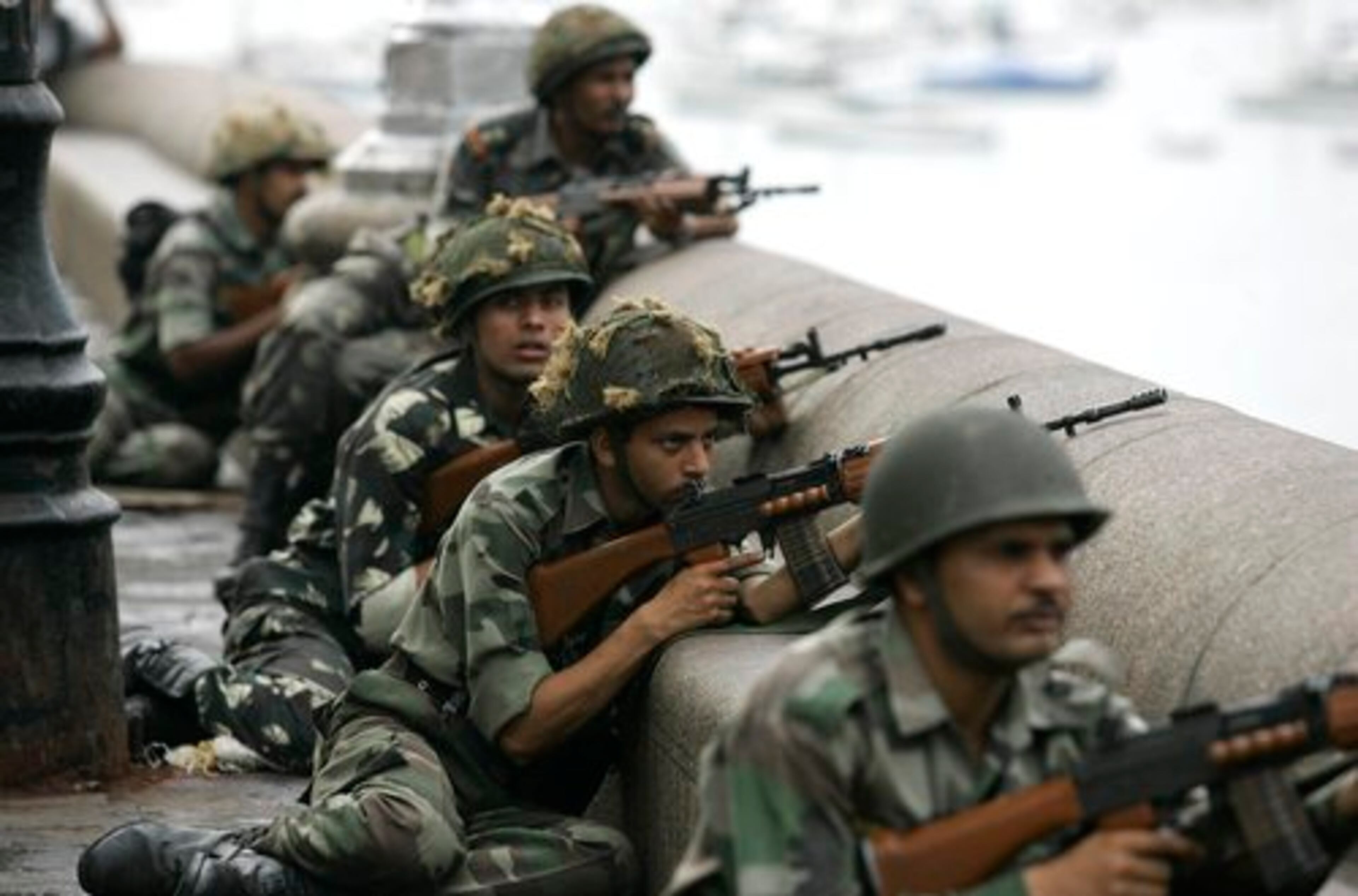 Indian soldiers take cover on the waterfront as they surround the Taj Mahal Hotel near the end of the bloody battle.