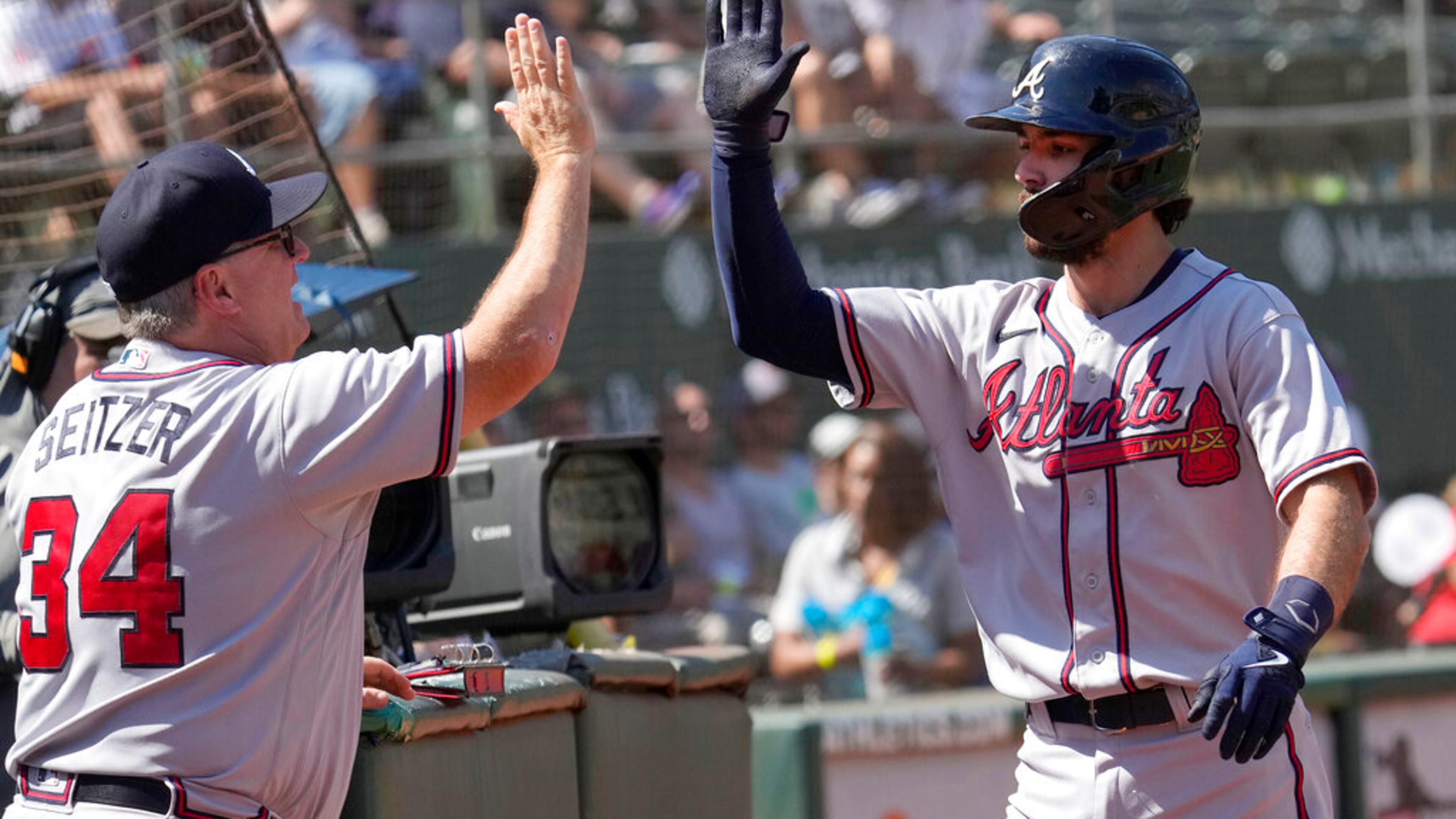 Atlanta Braves' Dansby Swanson, right, high fives hitting coach Kevin Seitzer (34) after hitting a solo home run against Oakland Athletics during the sixth inning of a baseball game in Oakland, Calif., Wednesday, Sept. 7, 2022. (AP Photo/Tony Avelar)