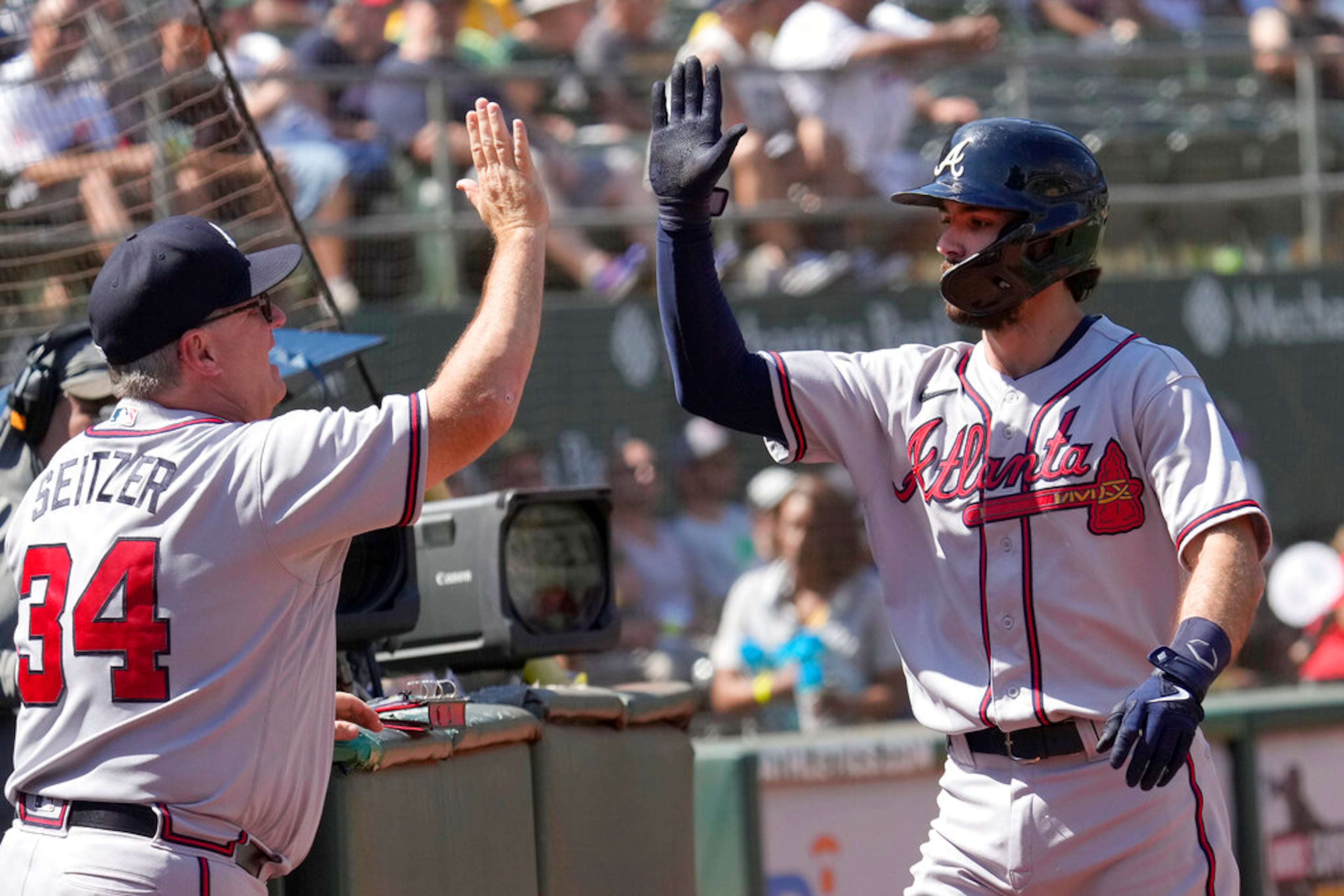 Atlanta Braves' Dansby Swanson, right, high fives hitting coach Kevin Seitzer (34) after hitting a solo home run against Oakland Athletics during the sixth inning of a baseball game in Oakland, Calif., Wednesday, Sept. 7, 2022. (AP Photo/Tony Avelar)