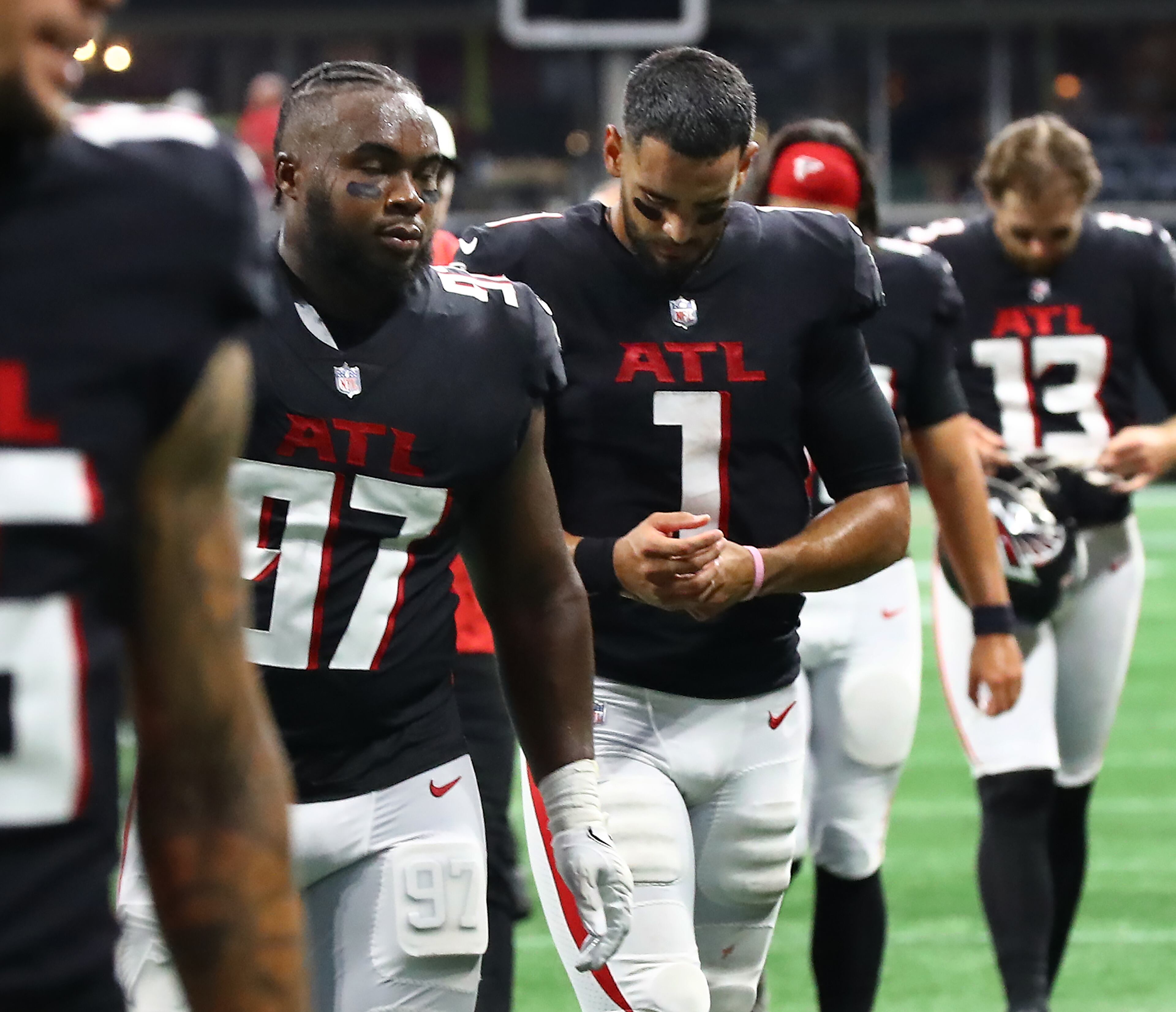 Falcons defensive lineman Grady Jarrett and quarterback Marcus Mariota walk off the field dejected after falling in a heartbreaker Sunday. (Curtis Compton / Curtis Compton@ajc.com)