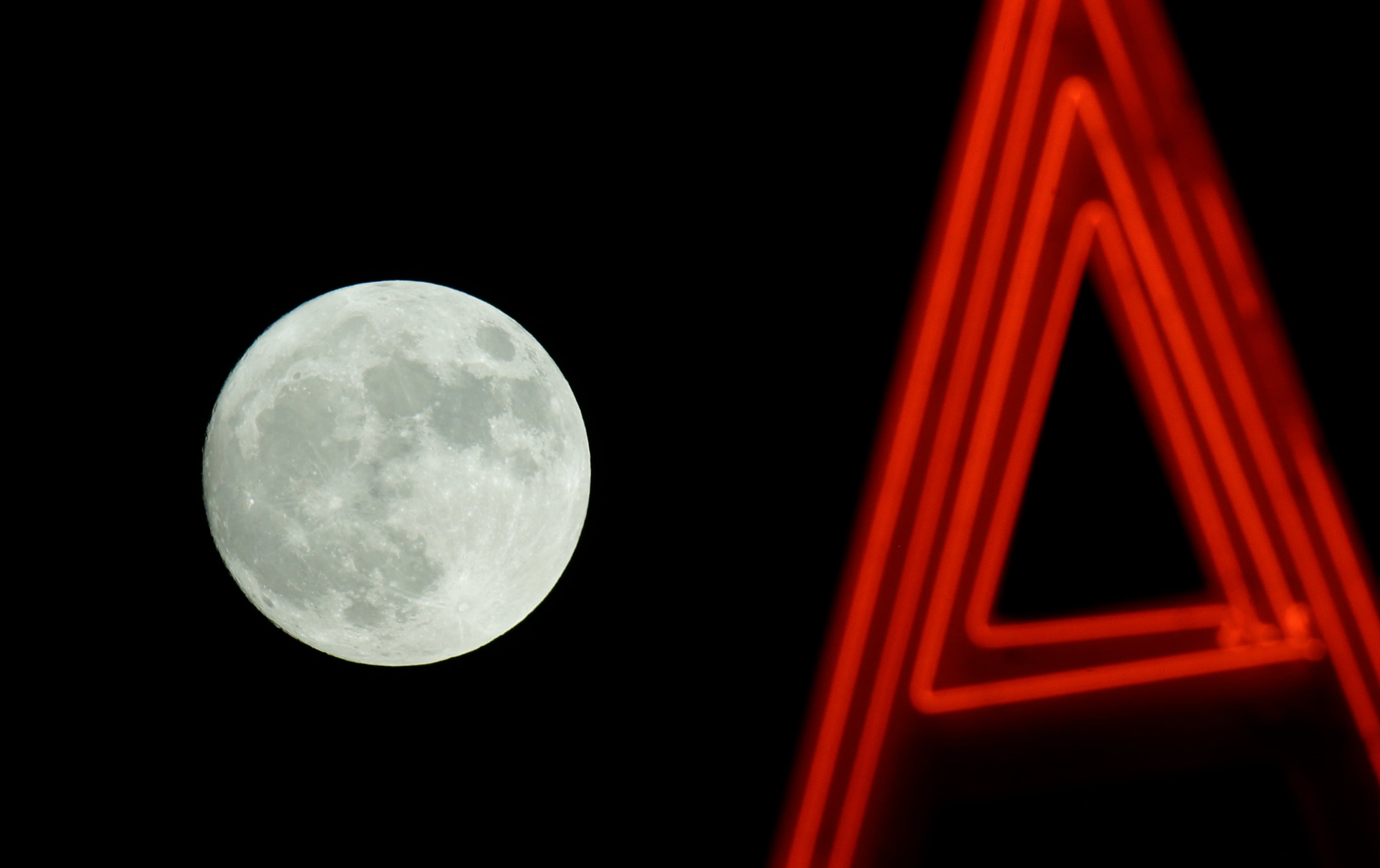 The moon rises behind a neon sign in Sacramento, Calif., Sunday, Nov. 13, 2016. Monday morning's supermoon will be the closet a full moon has been to the Earth since Jan. 26, 1948. (AP Photo/Rich Pedroncelli)