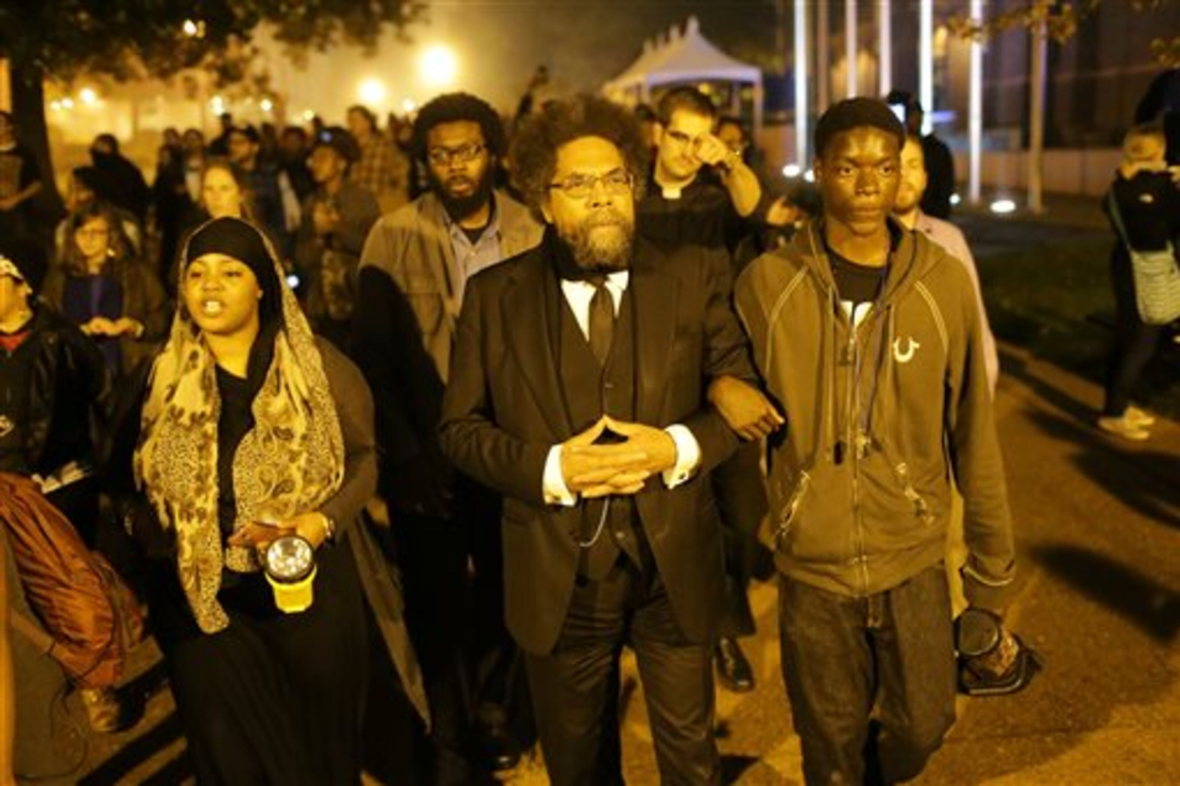 Philosopher Cornel West, center, and Joshua Williams, 18, right, march arm-in-arm with protesters towards the St. Louis University campus where protesters announced they were staging a sit-in, Monday, Oct. 13, 2014, in St. Louis, in reaction to the shooting this summer of a black, 18-year-old by a white police officer in Ferguson, Mo. (AP Photo/St. Louis Post-Dispatch, David Carson)