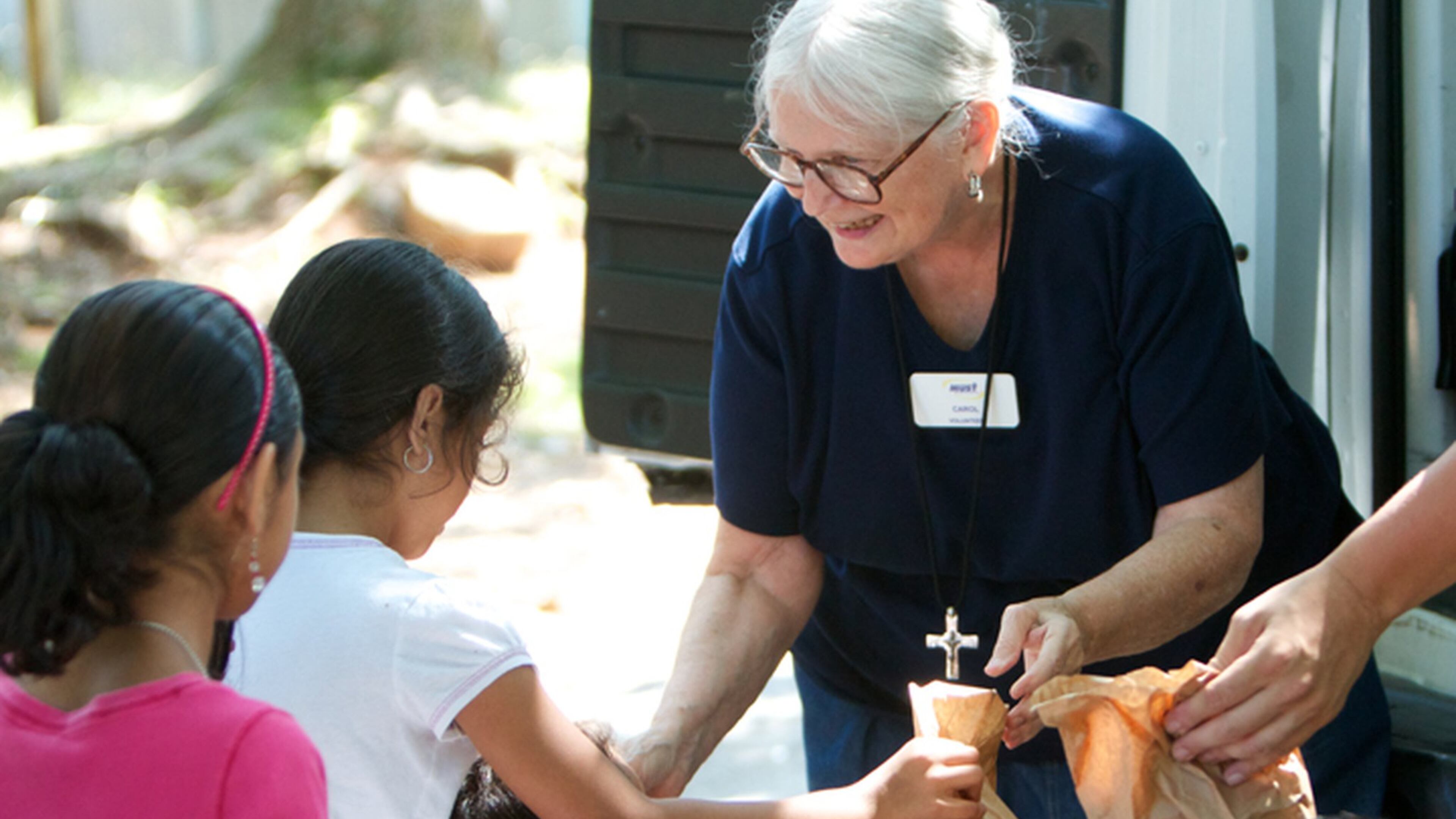 MUST summer lunch program founder Carol Hunt hands out sack lunches to children.