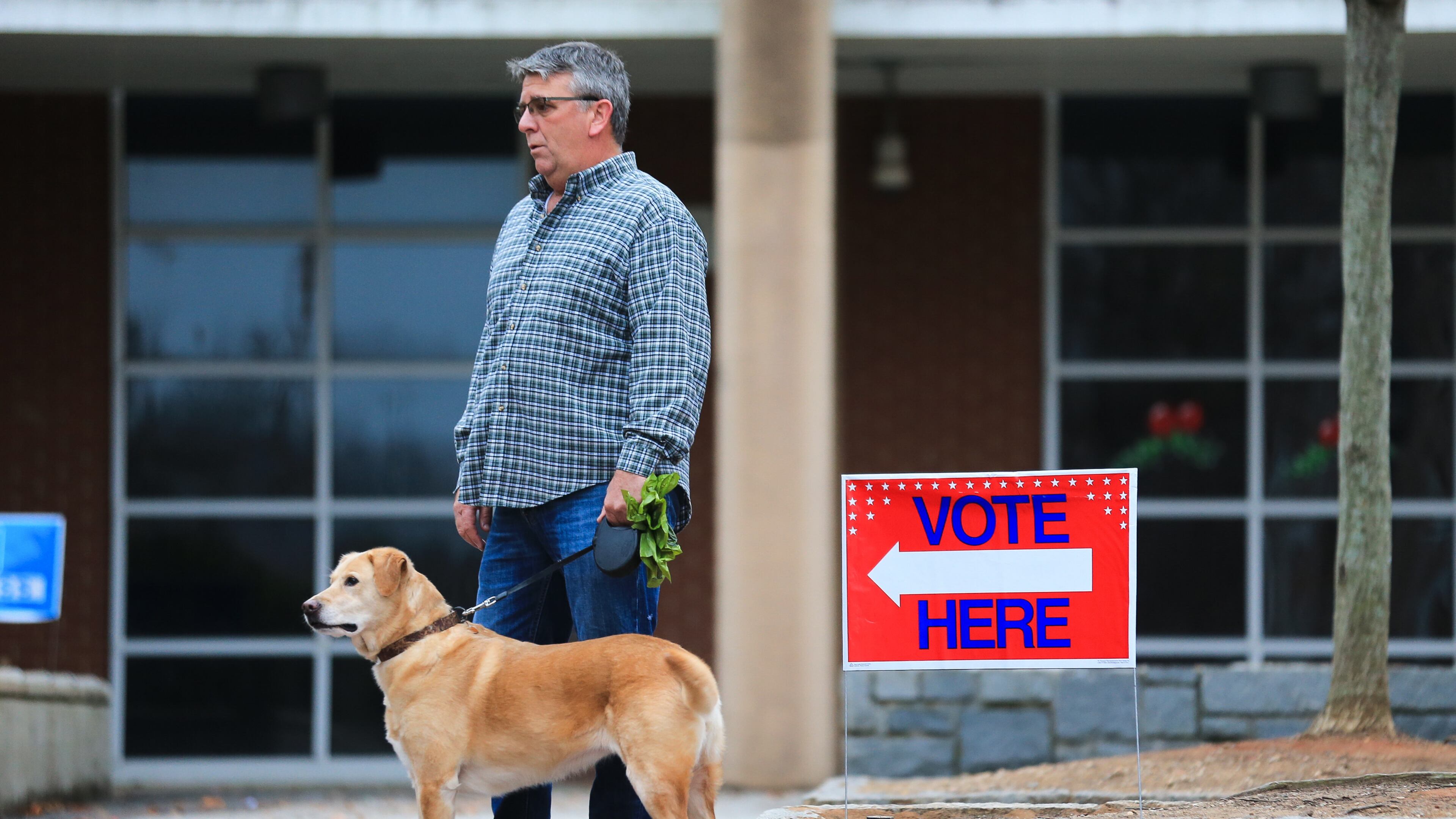 Harold Duvall gets pleasant weather Tuesday morning as he waits with his dog Riley for his wife to vote at Grady High School. But wet weather is on the way.