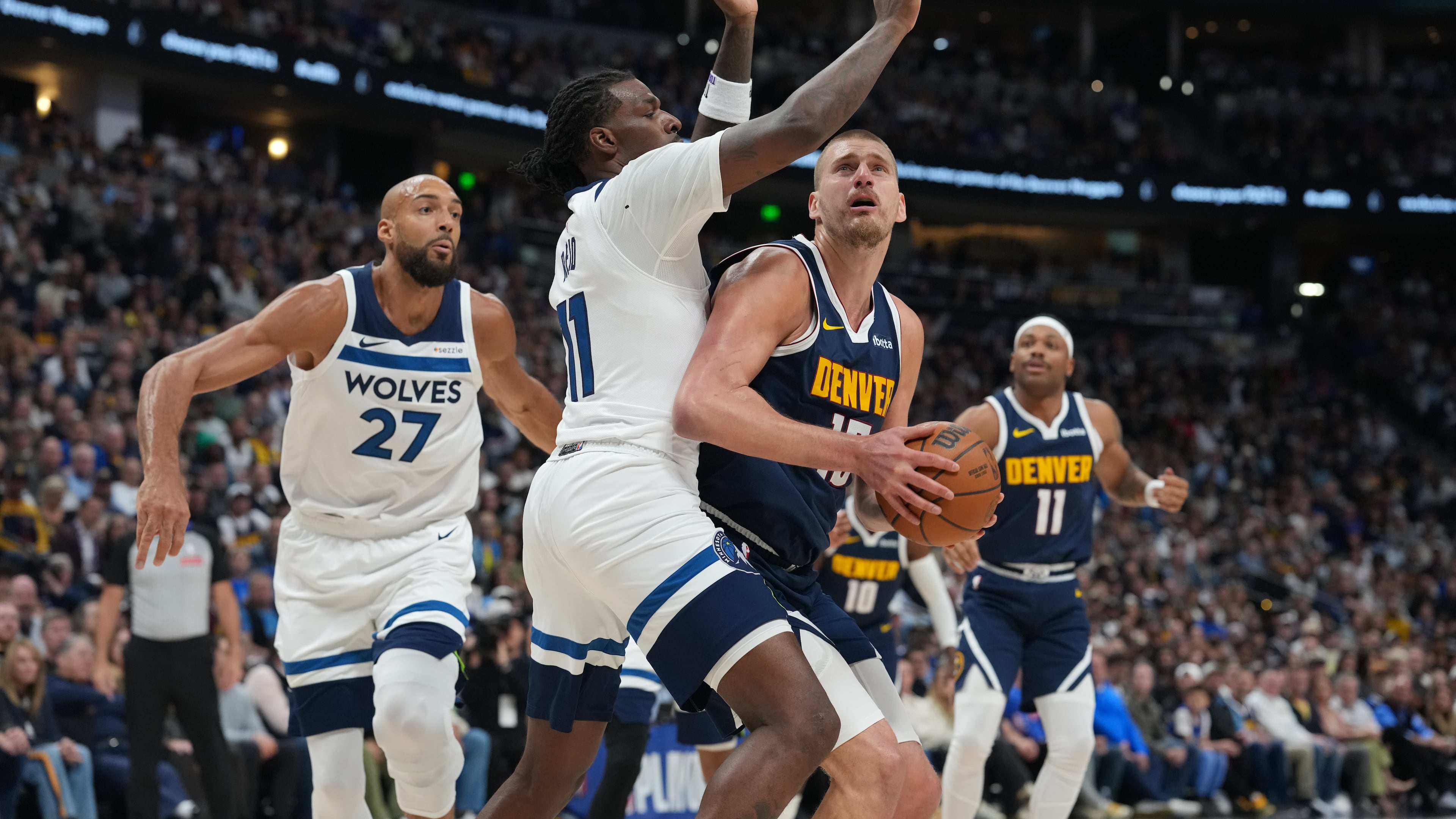 Denver Nuggets center Nikola Jokic, front right, drives the lane as Minnesota Timberwolves centers Naz Reid, center left, and Rudy Gobert, left, defend in the first half in Game 5 of a first-round NBA playoffs basketball series Monday, April 27, 2026, in Denver. (AP Photo/David Zalubowski)